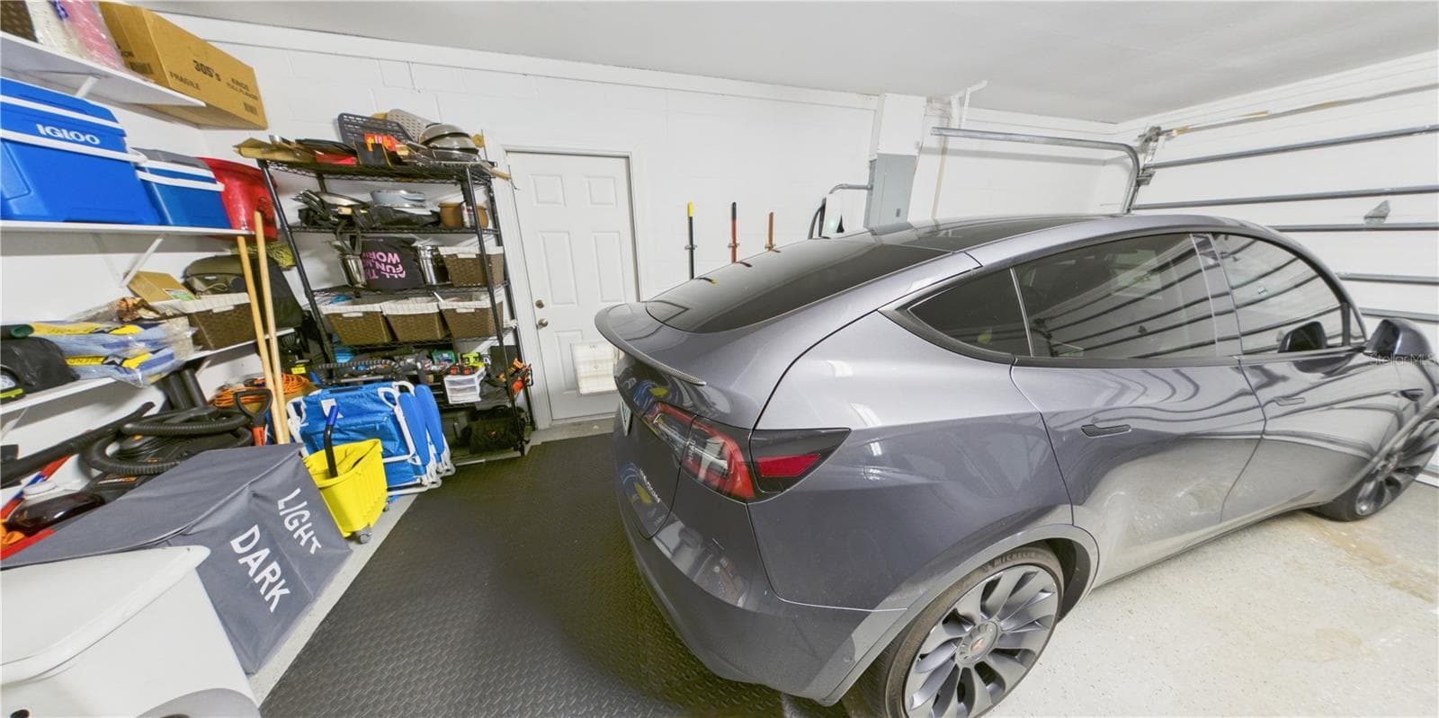 Two car garage with storage shelving and wall mounted Tesla charger. Vented with capped AC connection. - 16004 EAGLE RIVER WAY, TAMPA