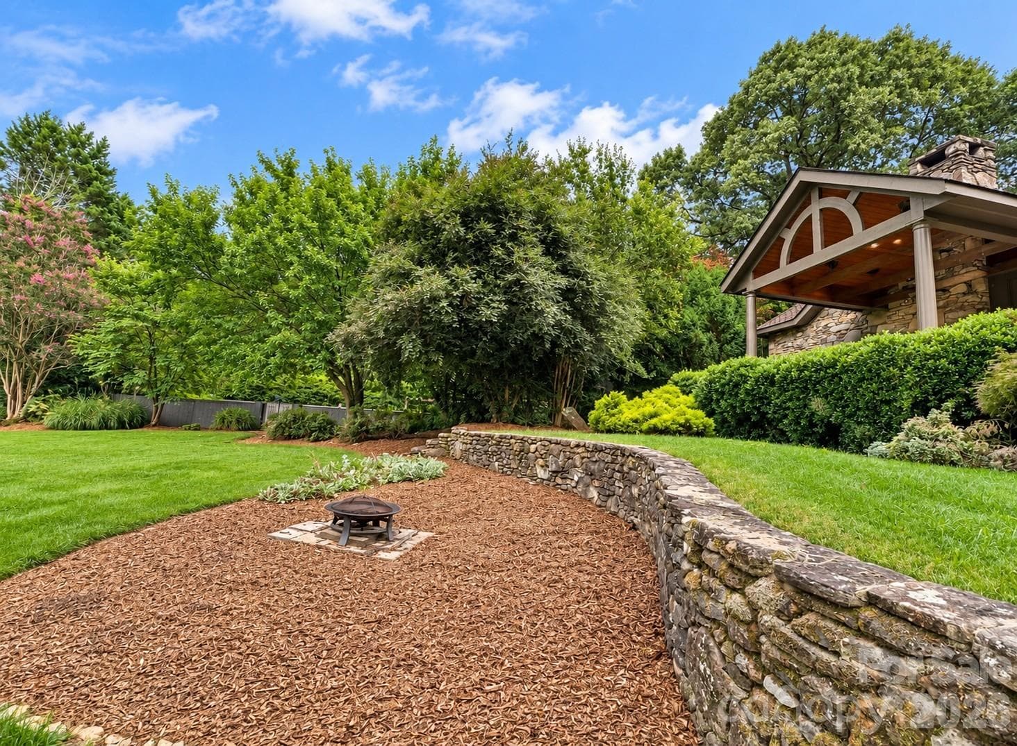 Covered area of wrap around porch, fire pit area and beautiful rock walls. - 4821 Elmhurst Drive NE, Hickory