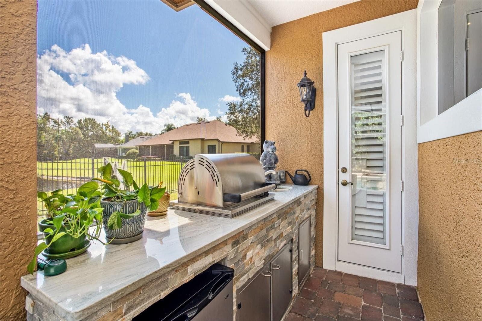 Stacked Stone Summer Kitchen under covered area with built-in propane tank and beverage fridge - 1220 PRESTIGE PT, OVIEDO