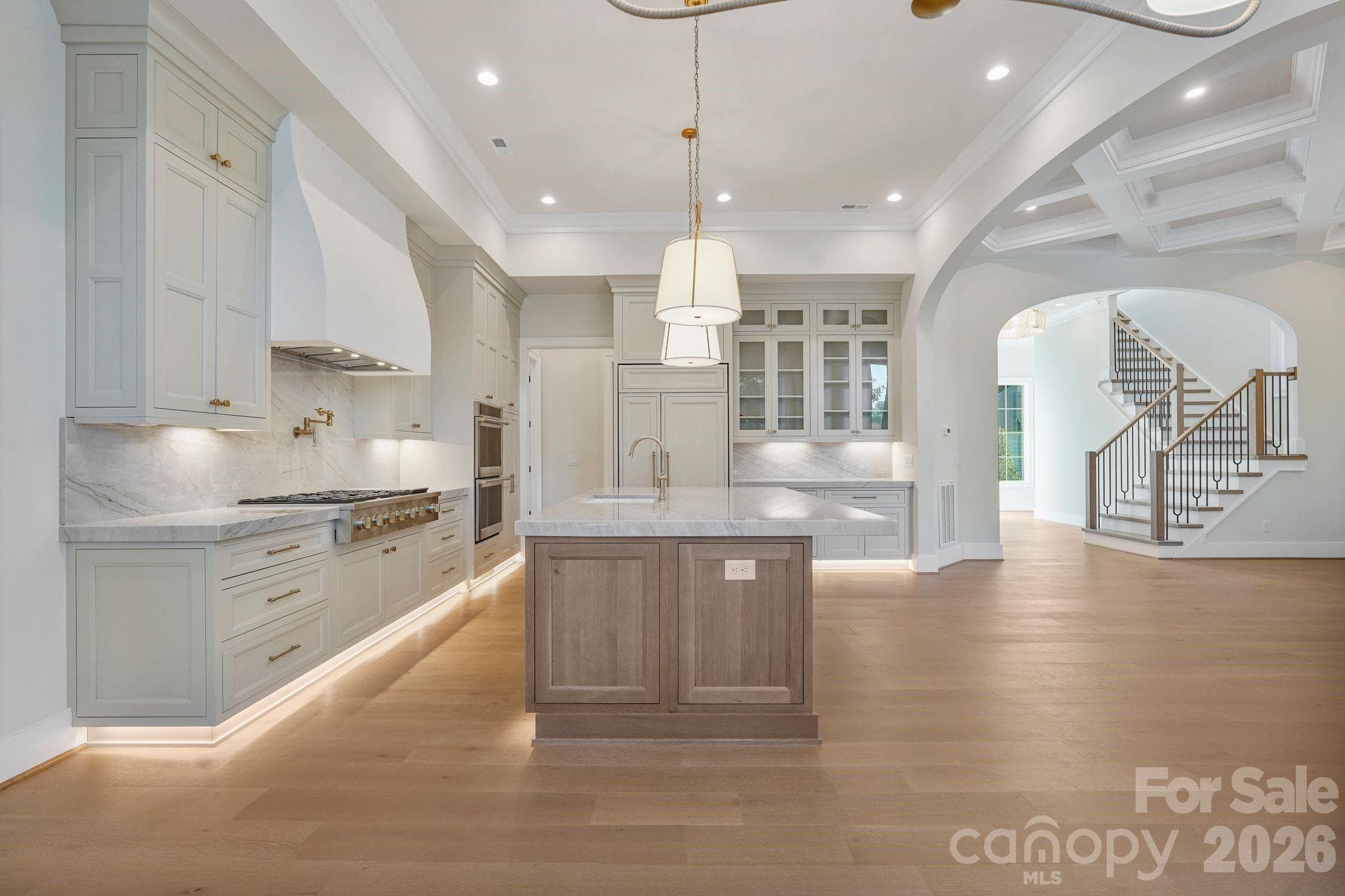 Side view of the kitchen highlighting seamlessly integrated panel-ready appliances, glass-front upper cabinetry, and refined custom finishes throughout. - 21216 Rio Oro Drive, Cornelius