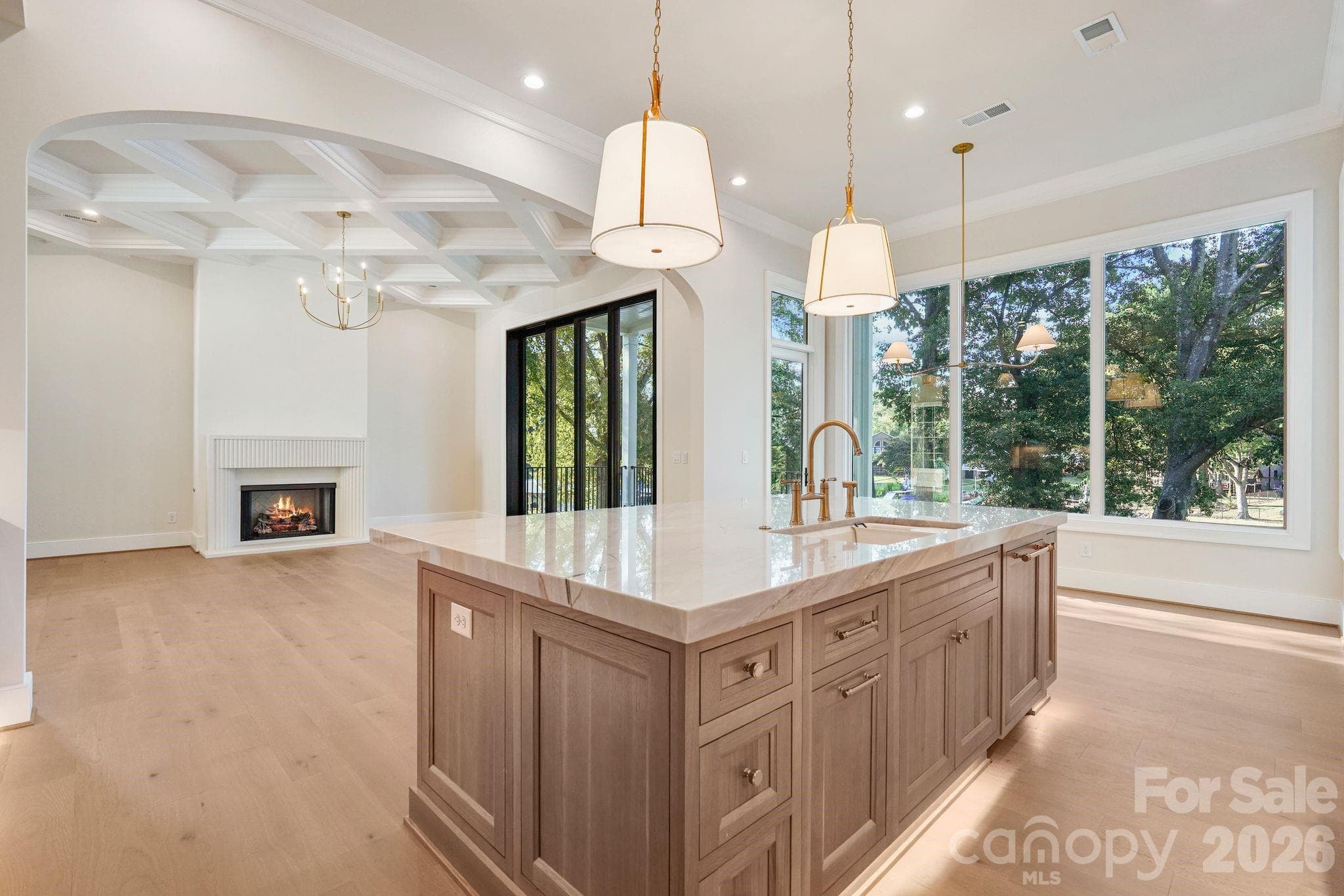 Open sightline from the kitchen into the family room, showcasing the seamless flow of the main level and abundant natural light from expansive windows. - 21216 Rio Oro Drive, Cornelius