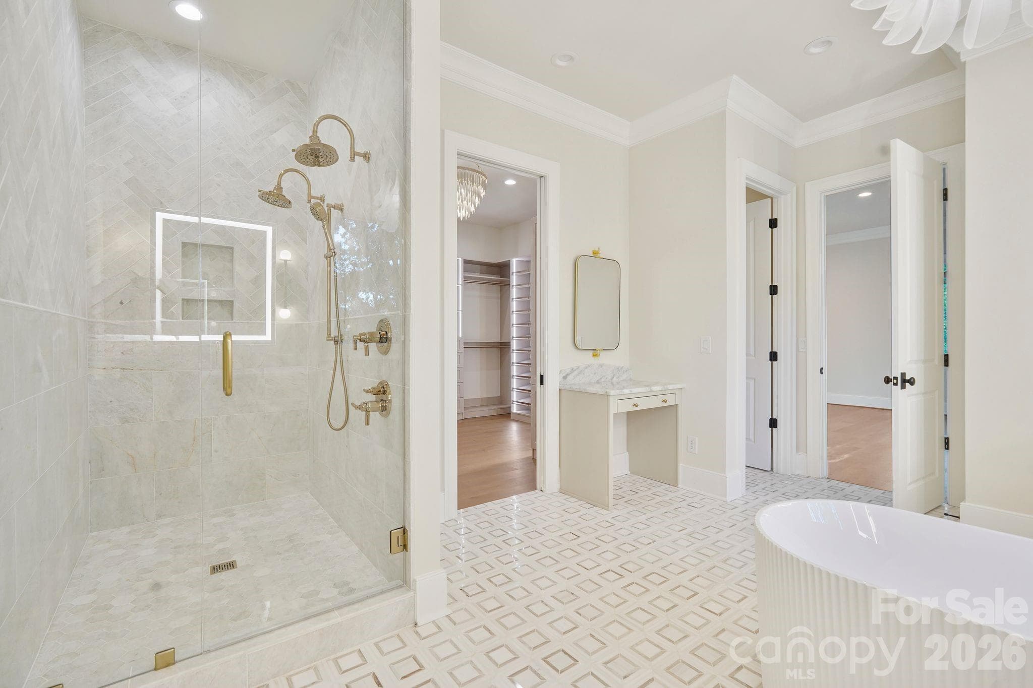 Luxurious marble shower featuring dual shower heads, floor-to-ceiling tile, and expansive frameless glass, complemented by a dedicated makeup vanity for a truly spa-inspired primary bath. - 21216 Rio Oro Drive, Cornelius