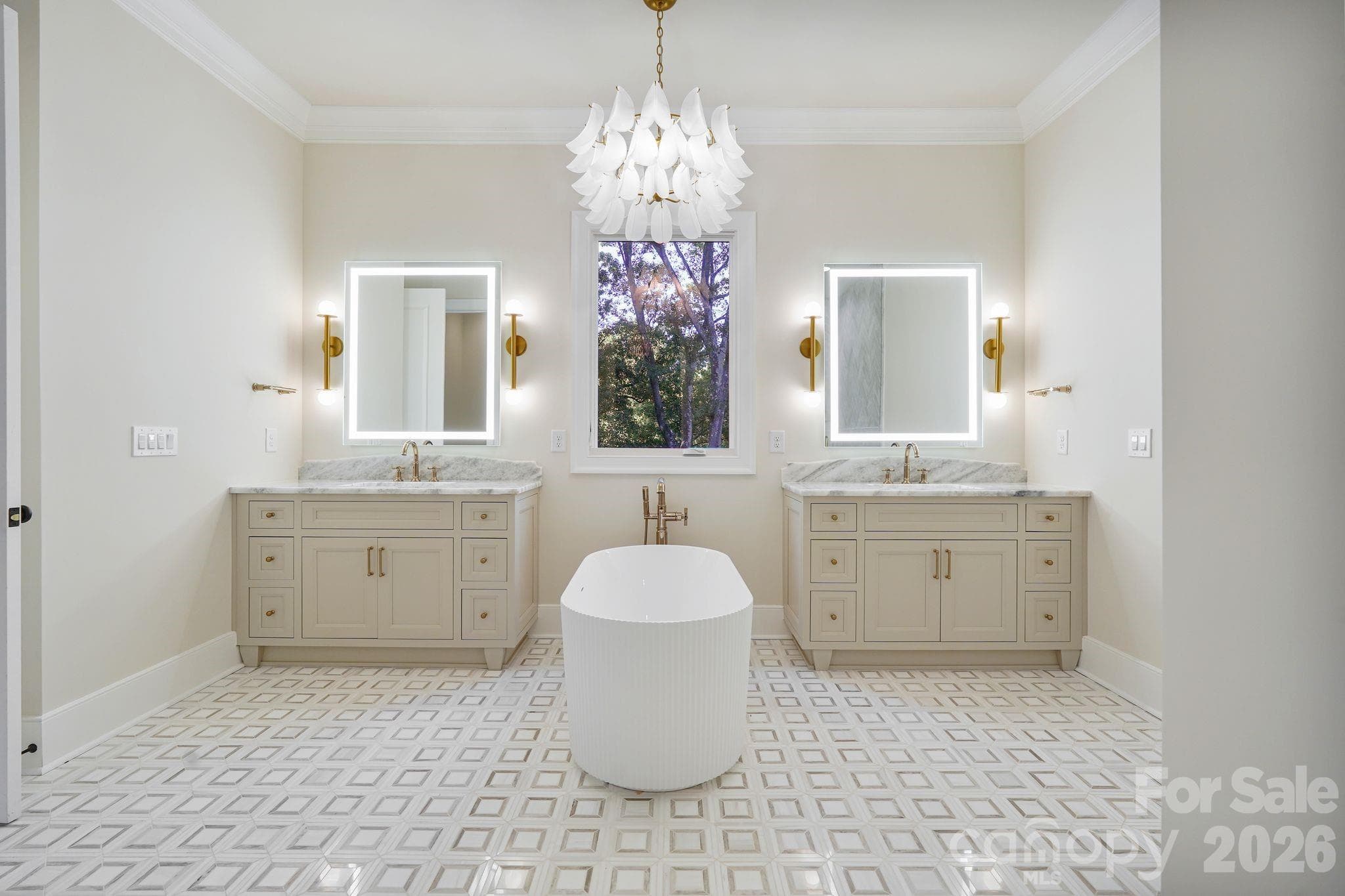 Spa-inspired primary bath featuring separate his-and-hers vanities, a sculptural freestanding tub with statement lighting, luxury illuminated mirrors, and a large window that fills the space with natural light. - 21216 Rio Oro Drive, Cornelius