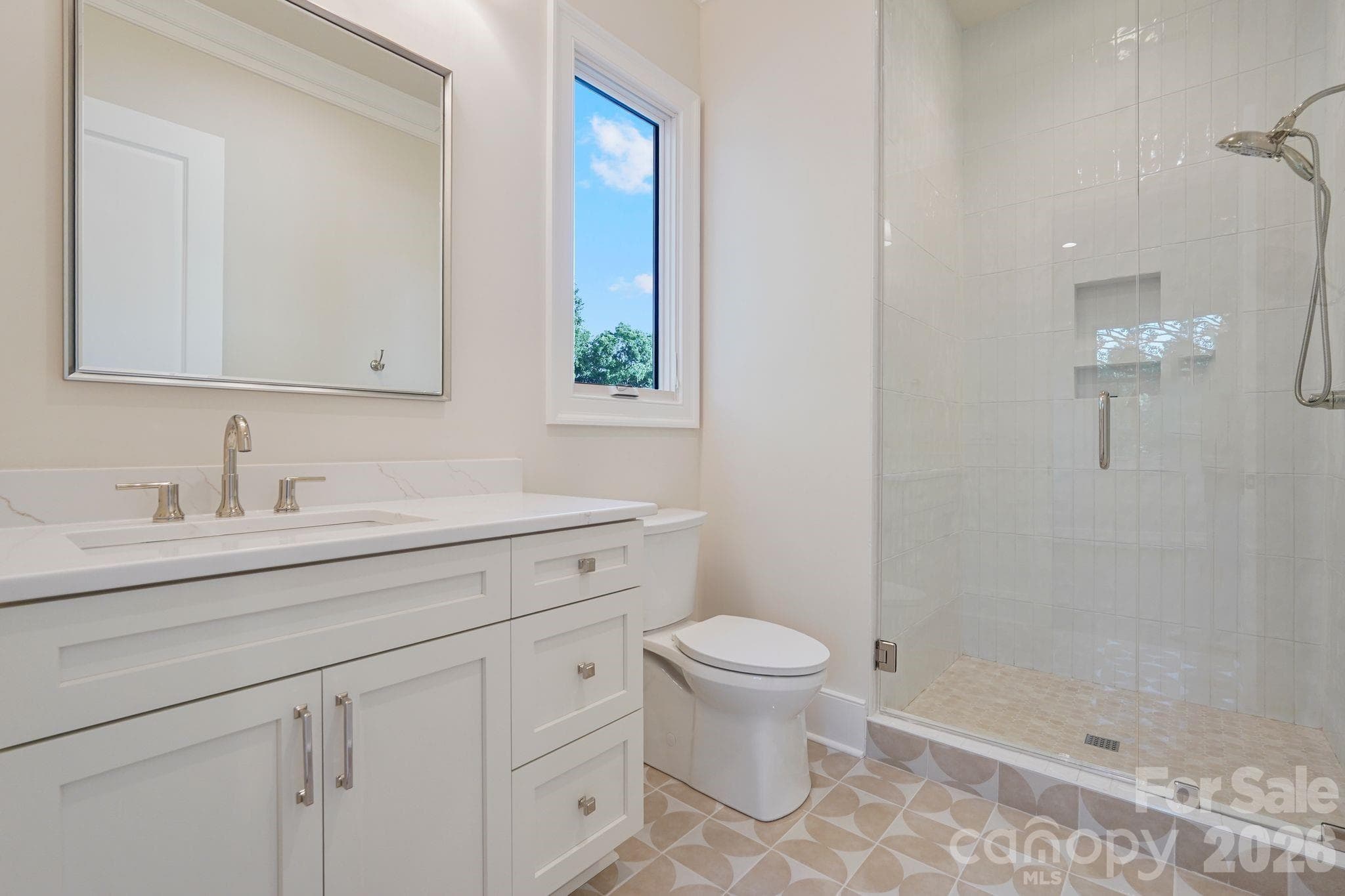 Bedroom 2 ensuite bath features floor-to-ceiling tile and a thoughtfully placed window that fills the space with natural light, creating a bright, elevated finish. - 21216 Rio Oro Drive, Cornelius