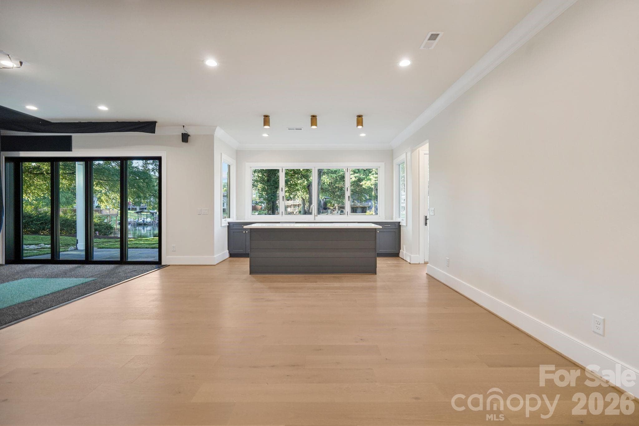 Luxury basement kitchenette featuring a built-in wine cooler and ice maker, plus an accordion-style window that opens directly to the outdoor living space for seamless indoor-outdoor entertaining. - 21216 Rio Oro Drive, Cornelius