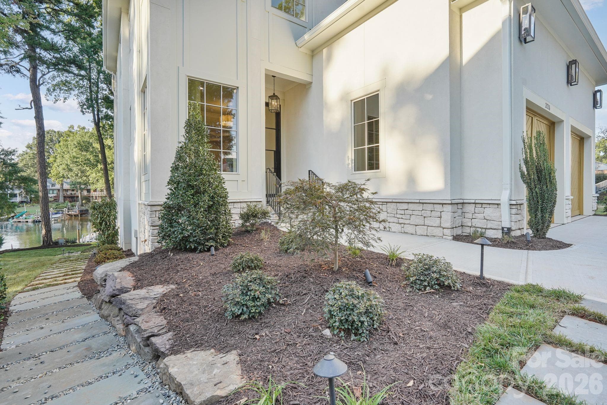 Professionally designed luxury landscaping enhanced by architectural night lighting, beautifully highlighting the home and grounds after sunset - 21216 Rio Oro Drive, Cornelius