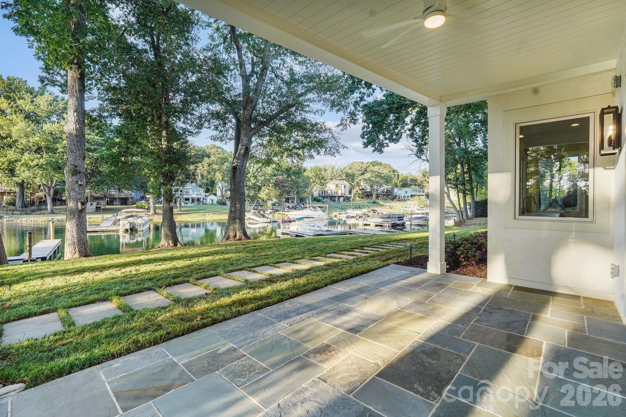Covered basement porch featuring flagstone flooring and a tongue-and-groove ceiling for an elevated outdoor living space. - 21216 Rio Oro Drive, Cornelius
