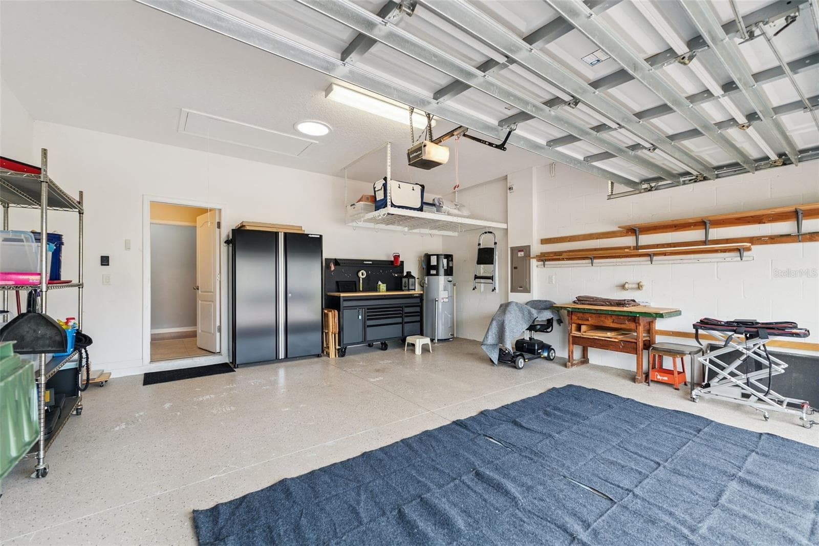 The garage equipped with 3 overhead storage racks, workbench with matching cabinetry, and an overhead solar skylight - 3541 RALEIGH DR, WINTER HAVEN