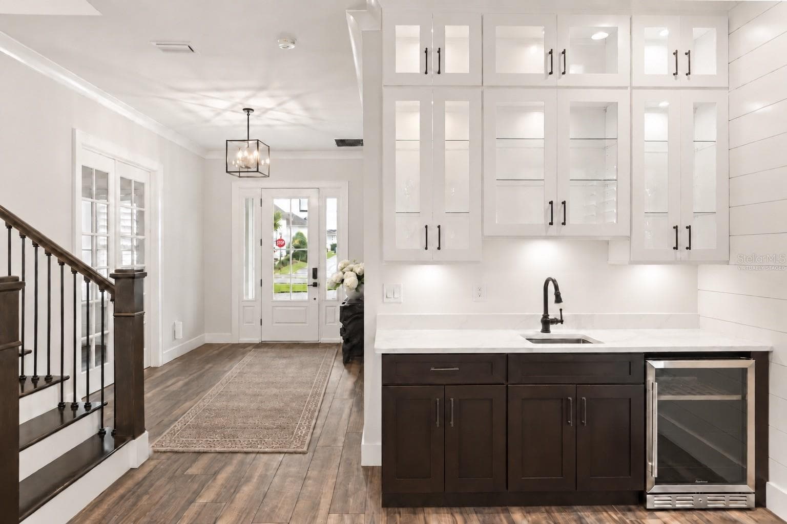 BUILT-IN WET BARA built-in wet bar with sink, beverage refrigerator and glass-front cabinetry sits just off the foyer, opening to the main living area for easy entertaining.Virtually staged, added runner and floral in foyer. - 907 CELADON ST, WINTER GARDEN