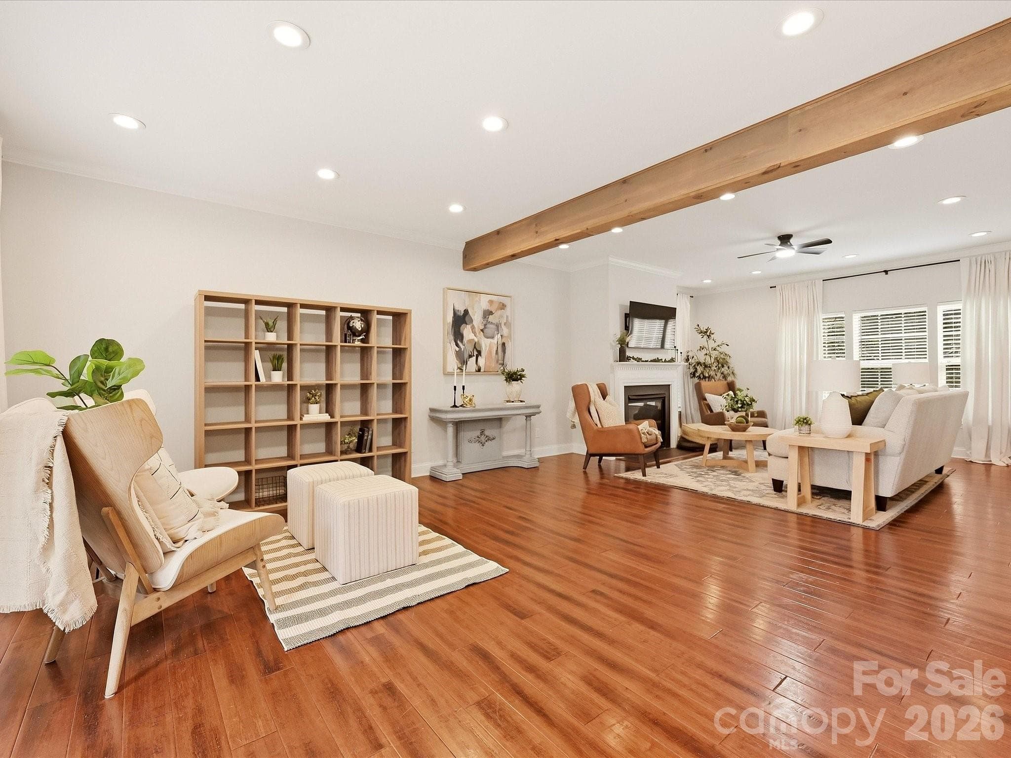 The spacious Great Room offers rich wood floors, a warm exposed beam, a cozy fireplace, and abundant natural light for an inviting everyday living space. - 16006 Lavenham Road, Huntersville
