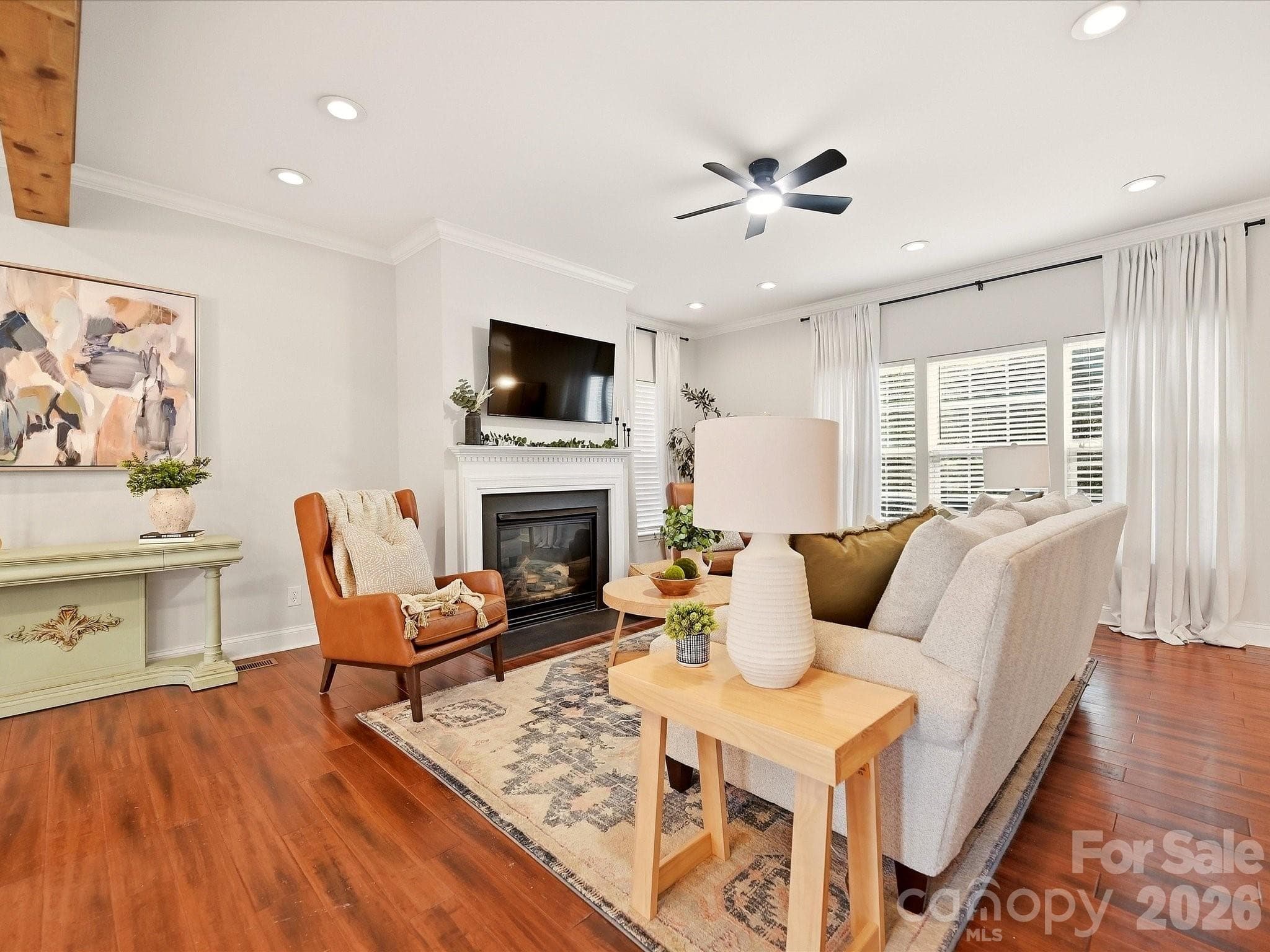 The inviting Great Room features a cozy fireplace, rich wood floors, abundant natural light, and plenty of space for comfortable everyday living. - 16006 Lavenham Road, Huntersville