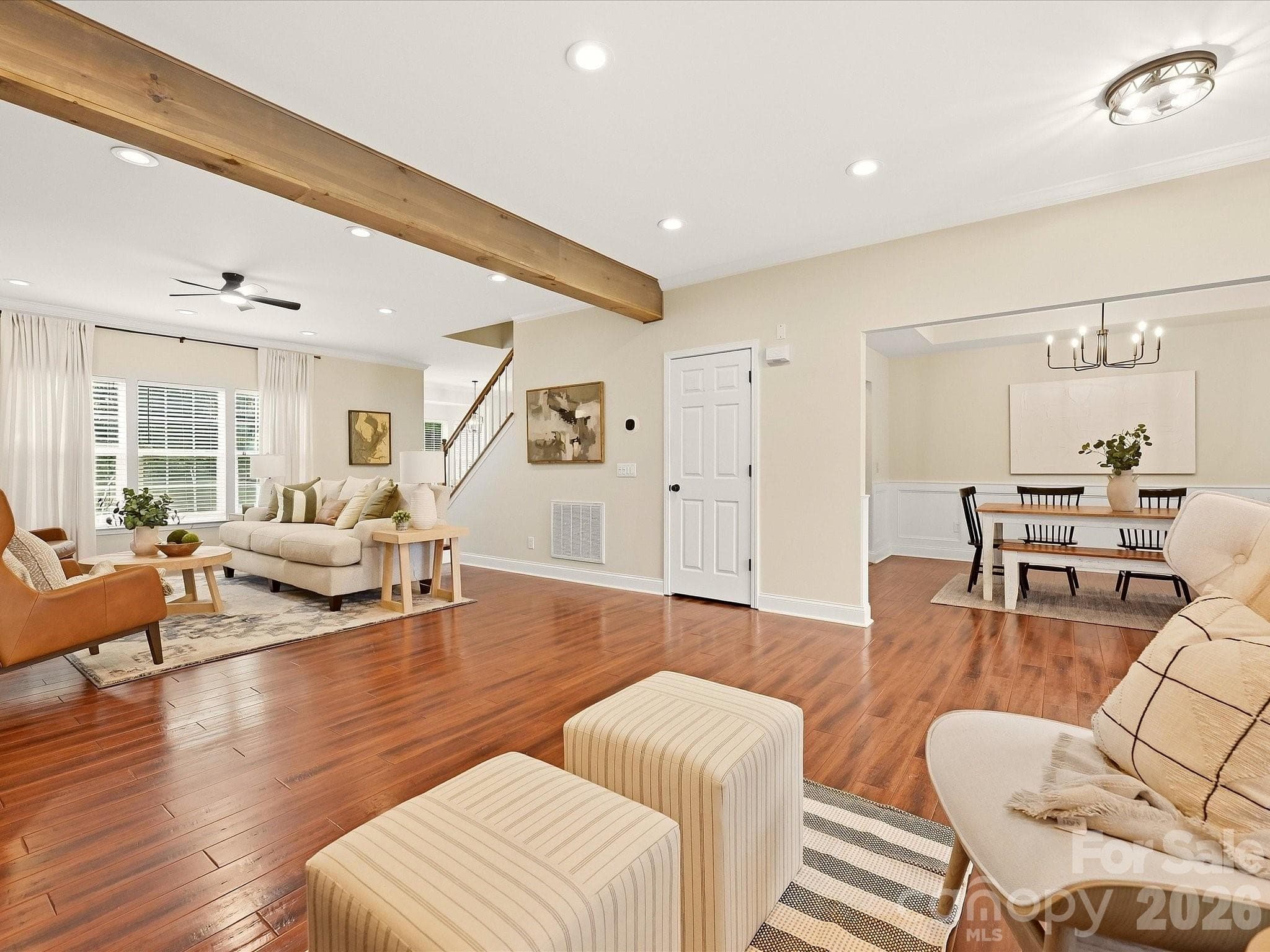 The spacious Great Room features rich wood floors, warm exposed beams, abundant natural light, and an open flow into the adjoining dining space. - 16006 Lavenham Road, Huntersville