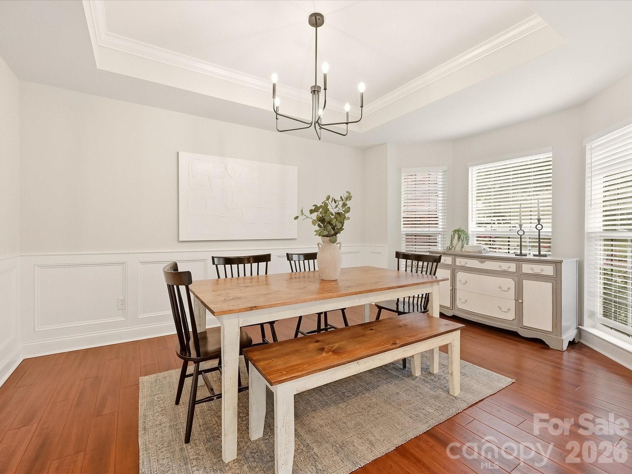 The bright dining room features a tray ceiling, classic wainscoting, a modern chandelier, and abundant natural light for an inviting place to gather. - 16006 Lavenham Road, Huntersville