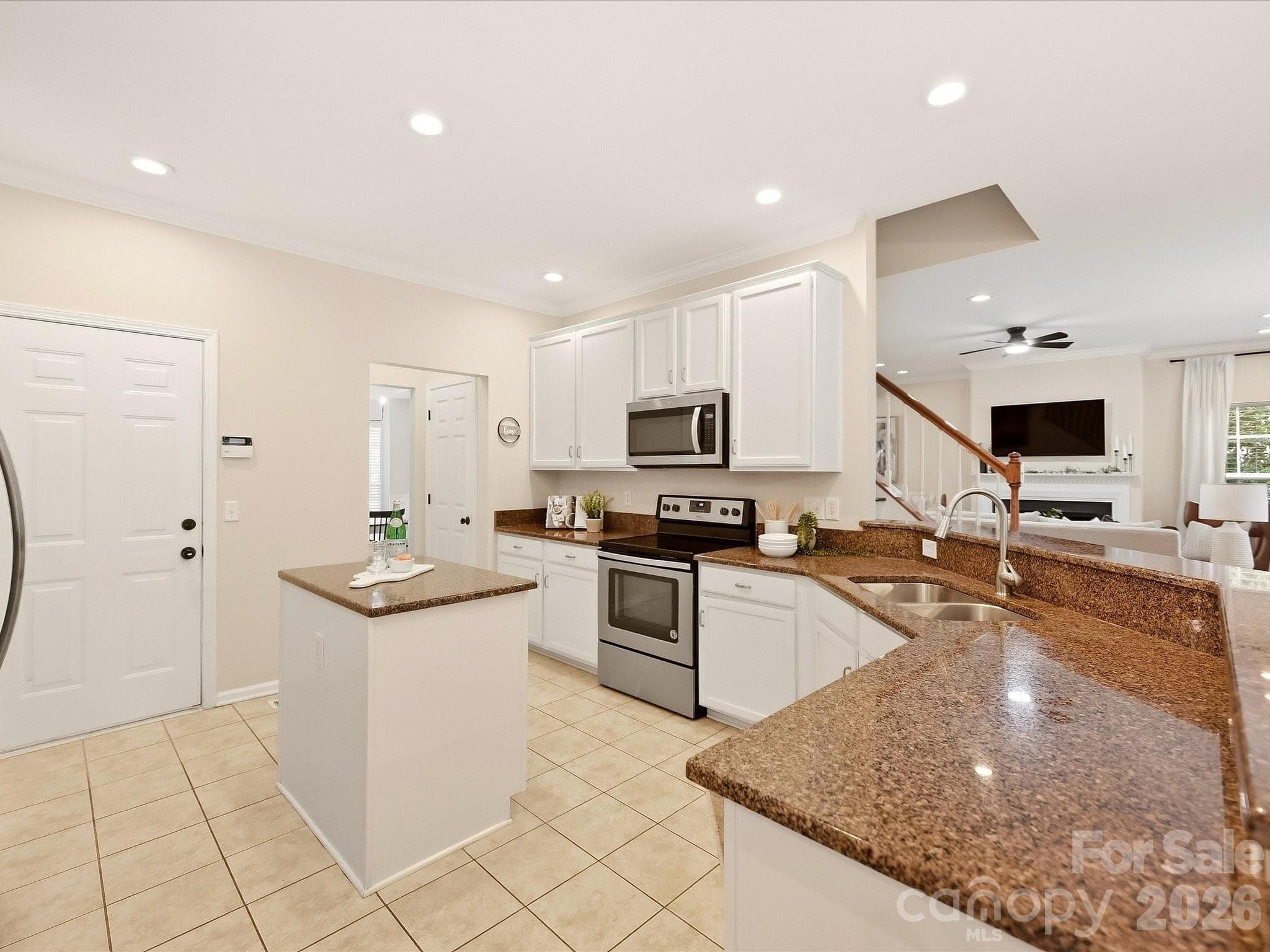 Another view of the bright kitchen highlights the white cabinetry, granite countertops, stainless steel appliances, center island, and open connection to the Great Room. - 16006 Lavenham Road, Huntersville