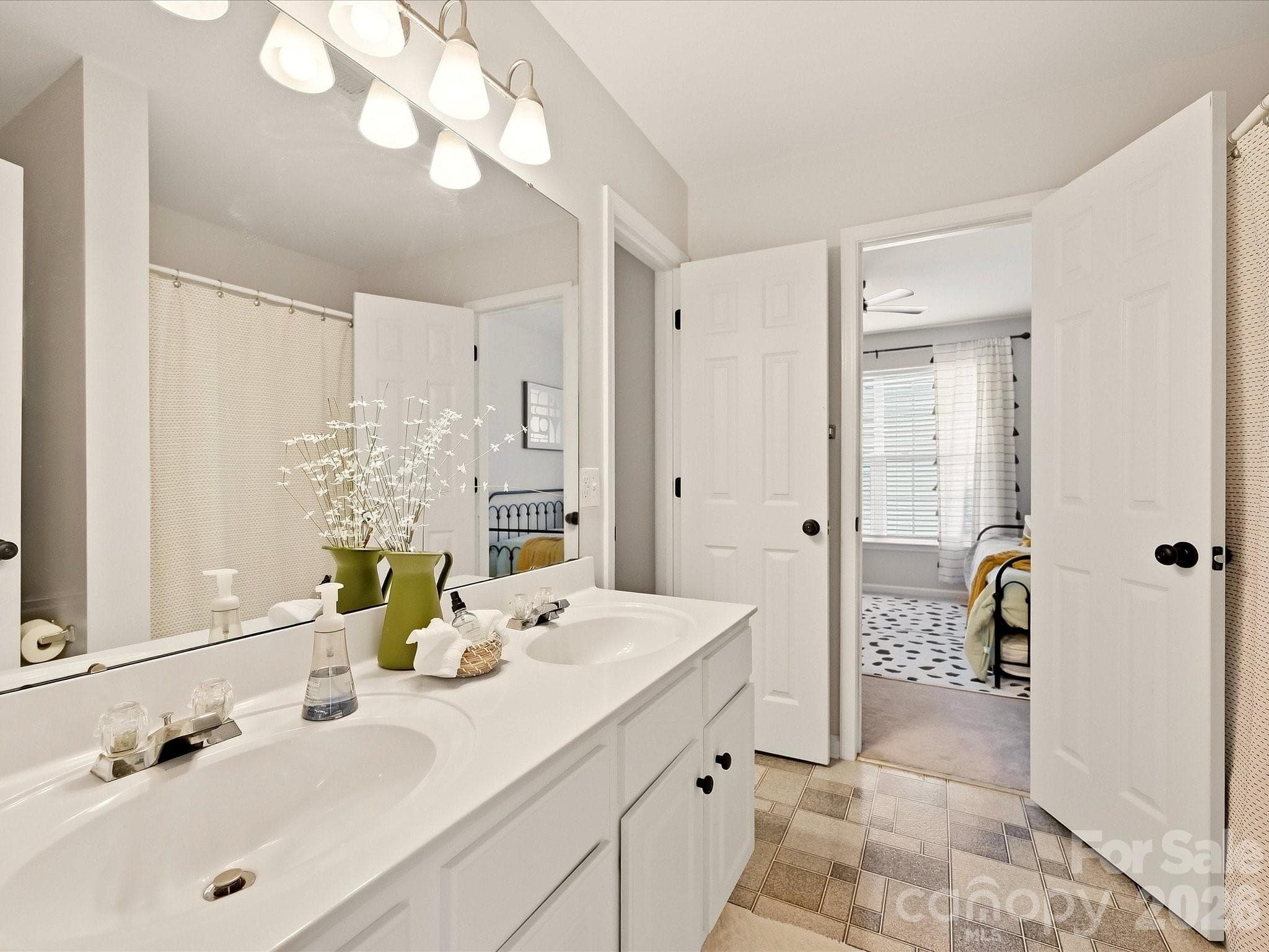 The Jack-and-Jill bath features a dual-sink vanity, tub/shower combination, and convenient access between two bedrooms for easy everyday functionality. - 16006 Lavenham Road, Huntersville