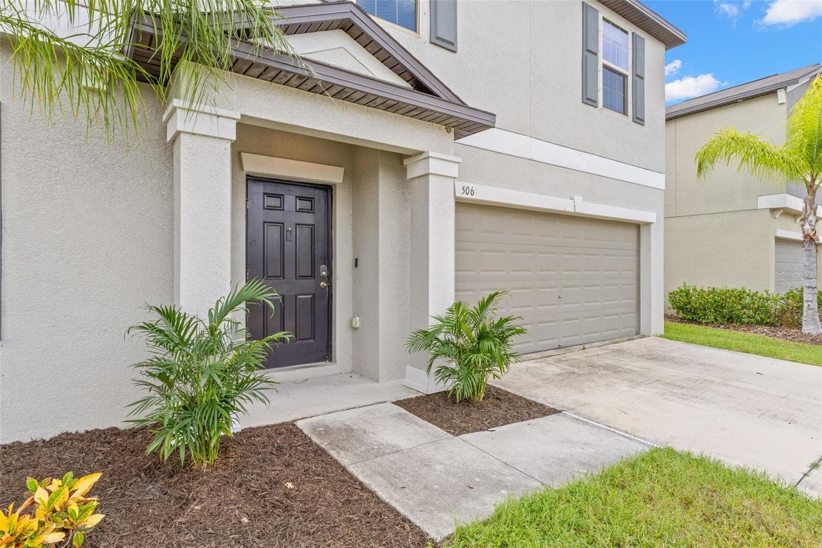 A covered front entry, tropical landscaping and a sheltered walkway come together to create a welcoming approach to the home. - 5061 WHITE CHICORY DR, APOLLO BEACH