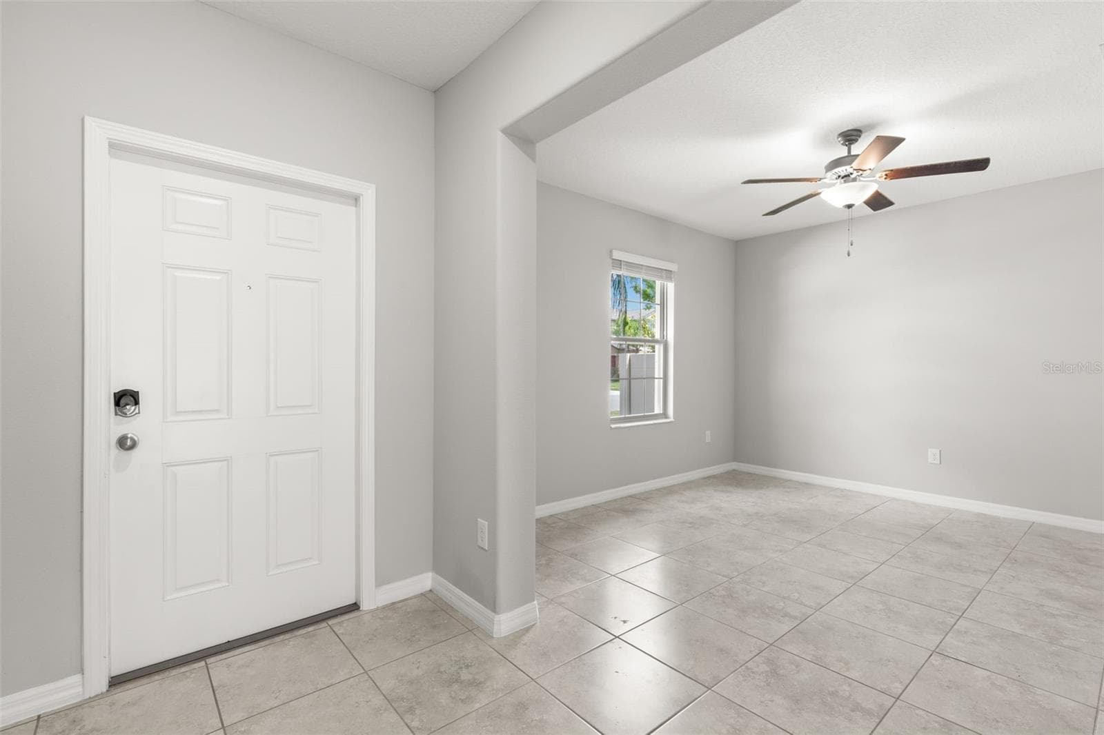 Just off the foyer, the bonus room/office serves as the home’s flexible fifth-bedroom space, with fresh neutral paint, tile flooring, a large window and ceiling fan; this room does not have a closet. - 5061 WHITE CHICORY DR, APOLLO BEACH