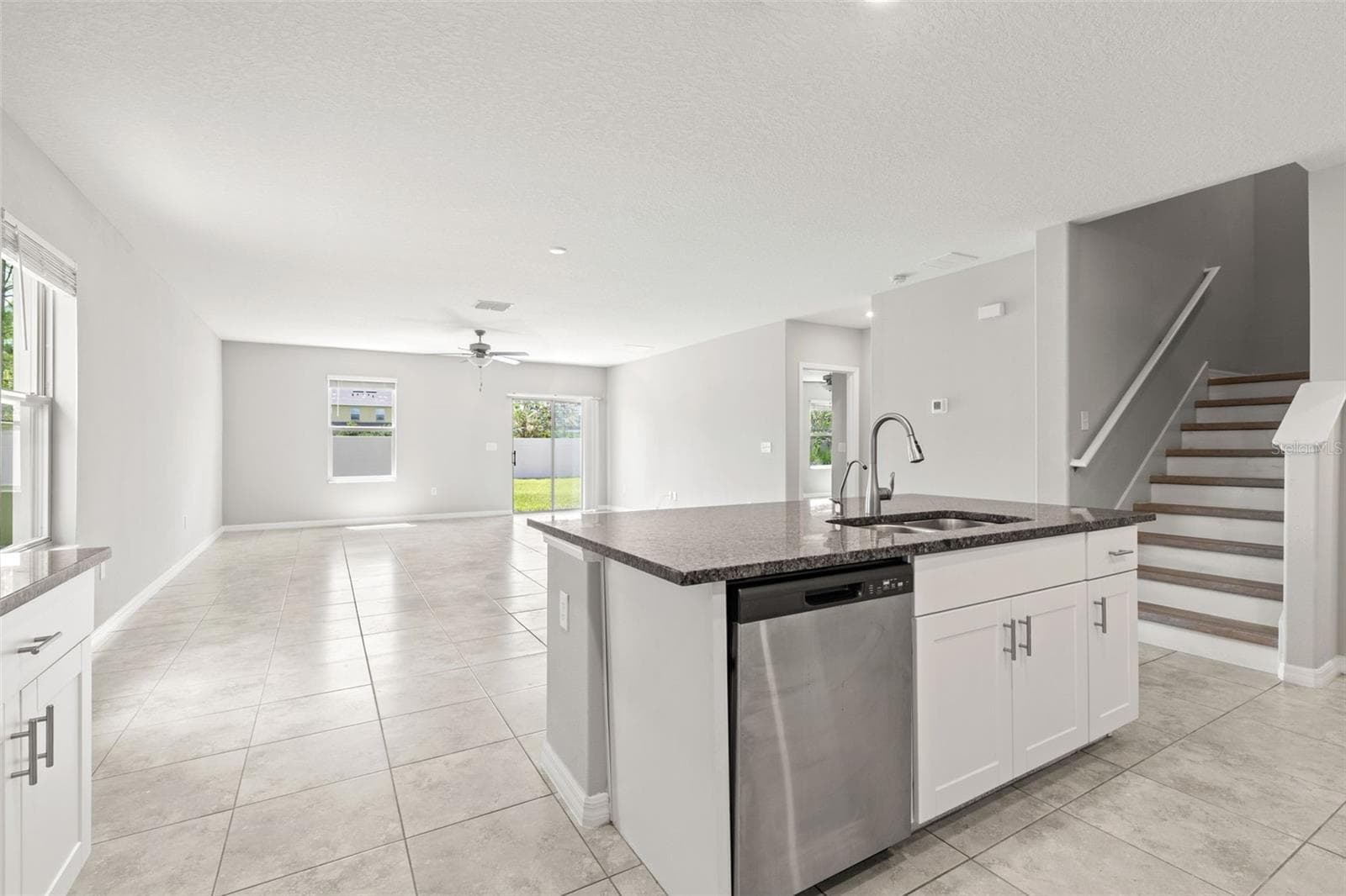 The granite-topped island anchors the kitchen with a double-basin sink, dishwasher and generous prep space, while the open layout connects directly to the great room and backyard. - 5061 WHITE CHICORY DR, APOLLO BEACH