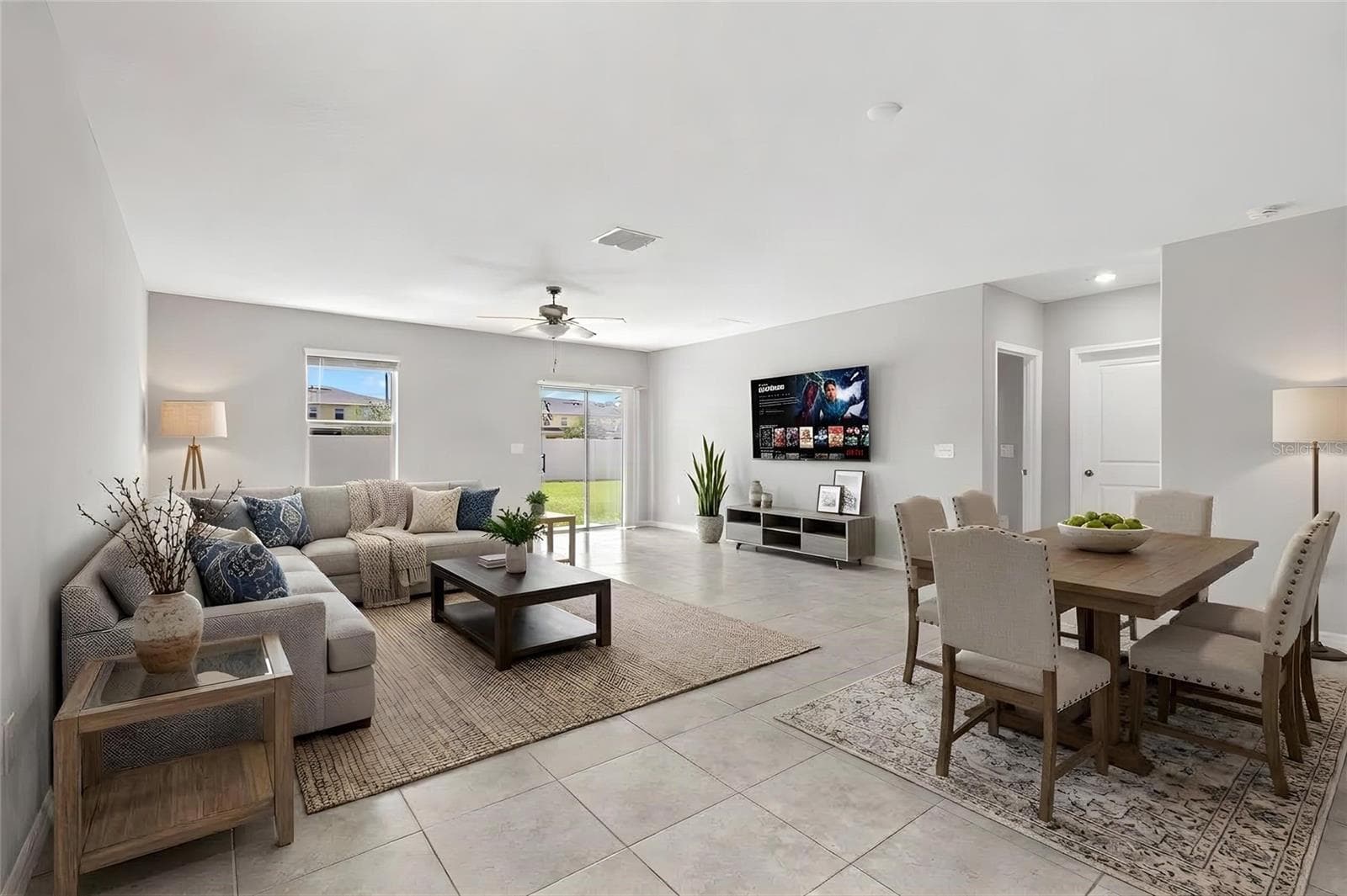 The great room offers plenty of space for both seating and dining, with fresh neutral paint, tile flooring and direct access to the backyard through sliding glass doors. - 5061 WHITE CHICORY DR, APOLLO BEACH