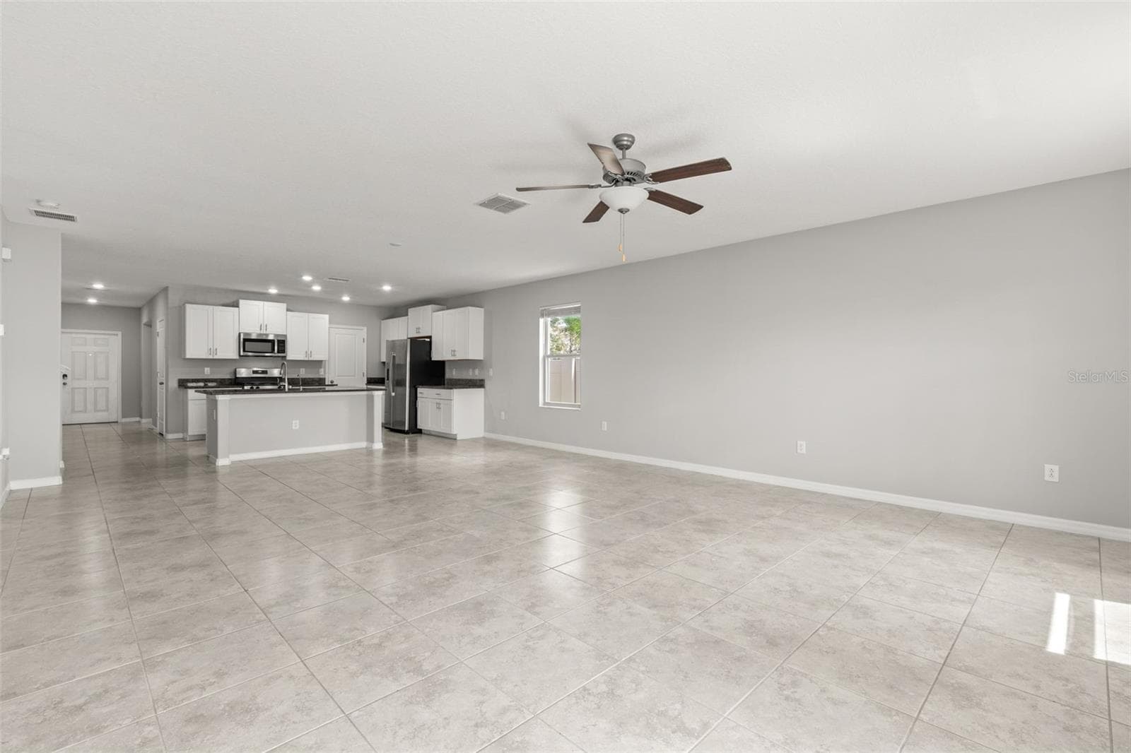 The great room’s generous proportions leave plenty of flexibility for multiple seating and dining arrangements, while the open connection to the kitchen keeps the main living spaces feeling expansive and easy to use. - 5061 WHITE CHICORY DR, APOLLO BEACH