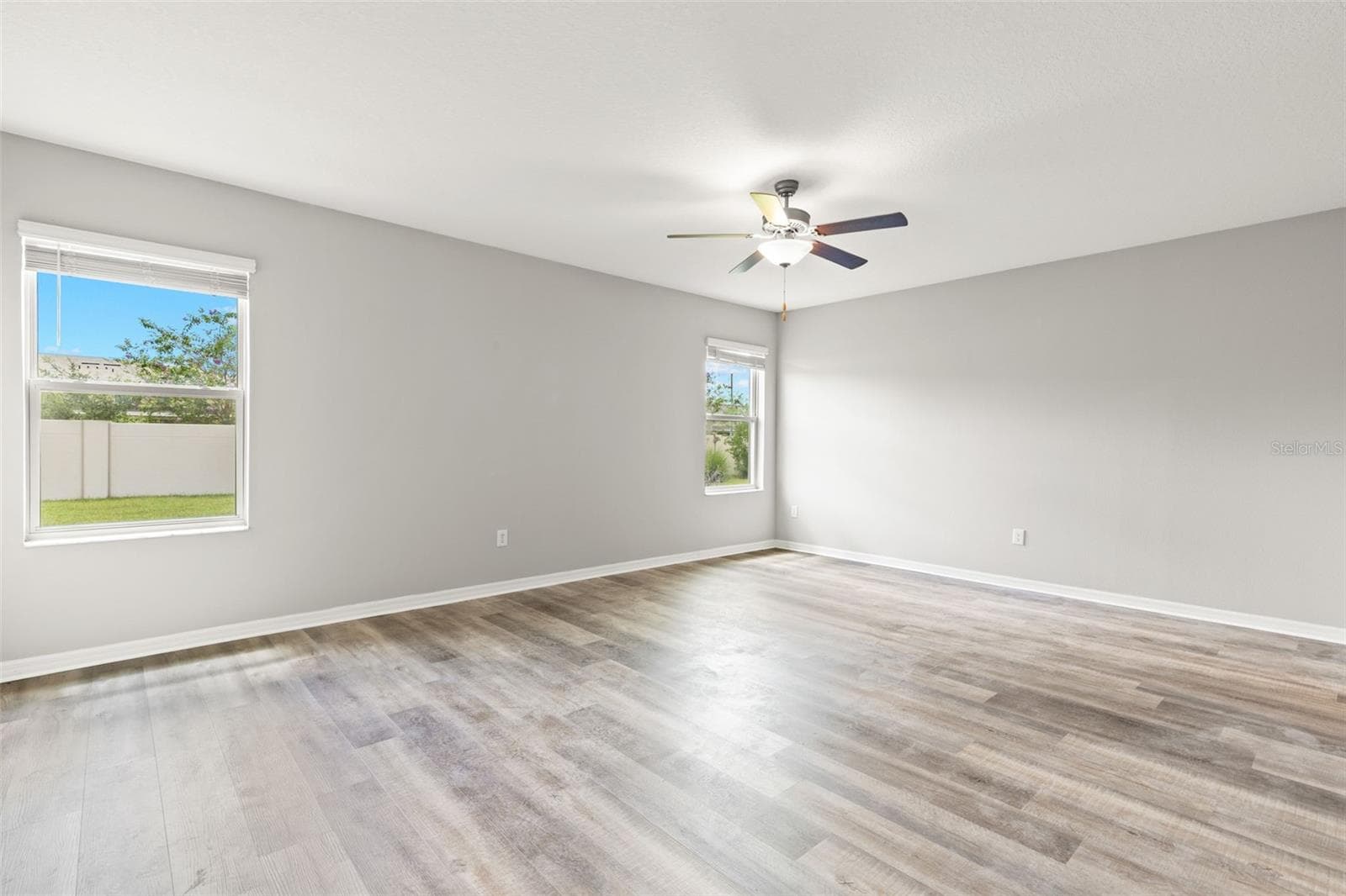 The first-floor primary bedroom offers generous proportions, two windows, fresh neutral paint and newly replaced laminate flooring, creating a bright, comfortable retreat away from the upstairs bedrooms. - 5061 WHITE CHICORY DR, APOLLO BEACH