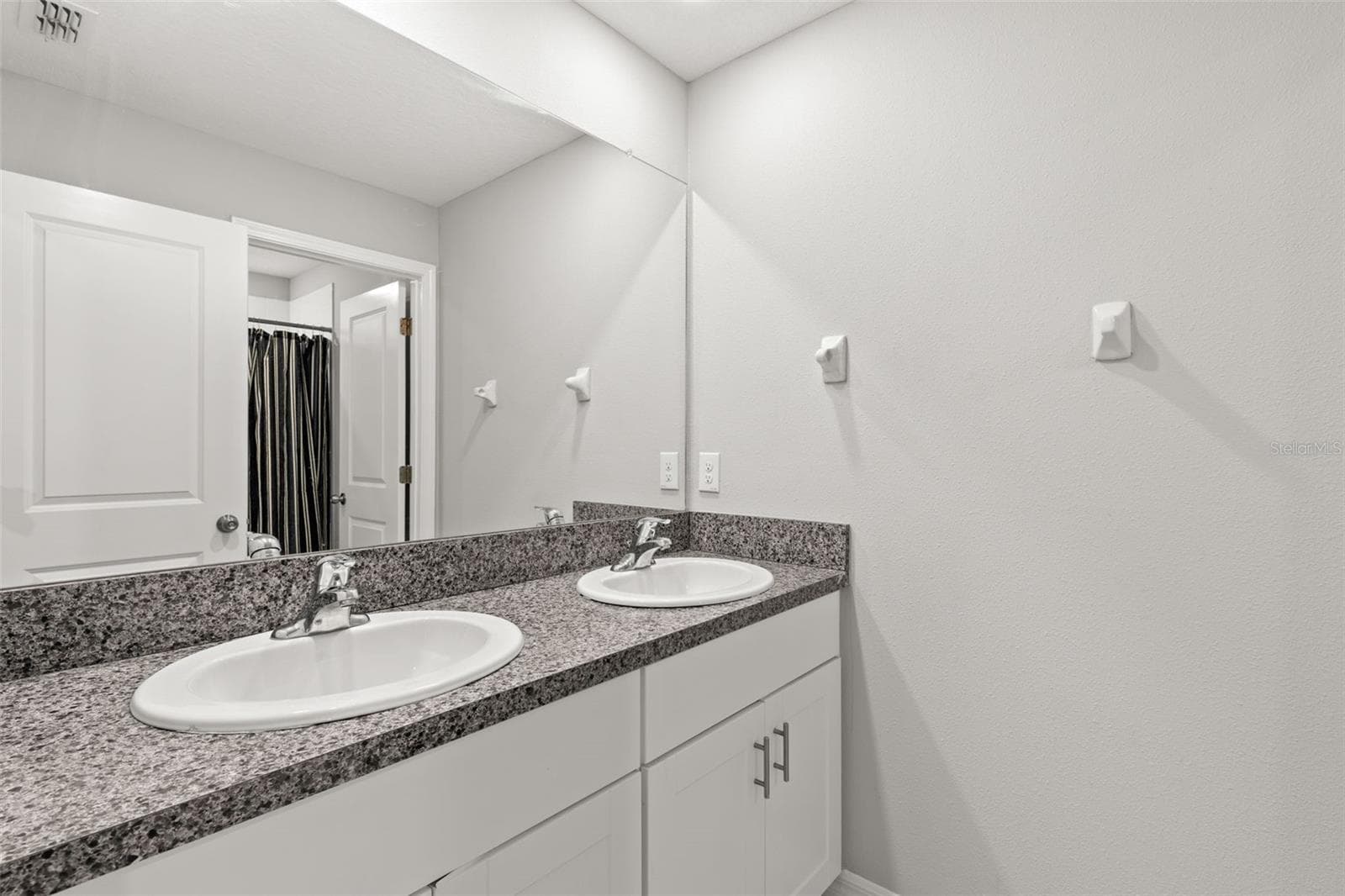 Bathroom 2 features a dual-sink vanity with granite countertops, generous cabinet storage and a large wall mirror, giving the upstairs bedrooms a practical shared bath. - 5061 WHITE CHICORY DR, APOLLO BEACH