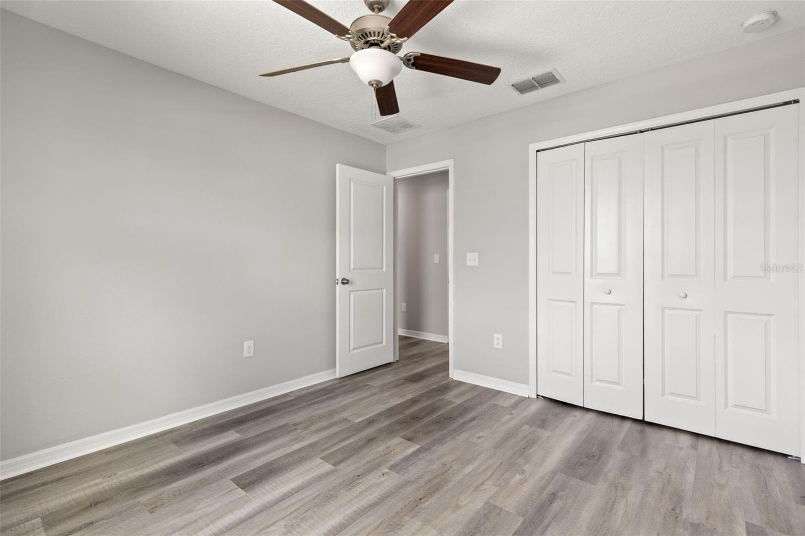 Bedroom 4 includes a wide double-door closet, newly replaced laminate flooring, fresh neutral paint and a ceiling fan, giving the room plenty of storage and flexibility. - 5061 WHITE CHICORY DR, APOLLO BEACH