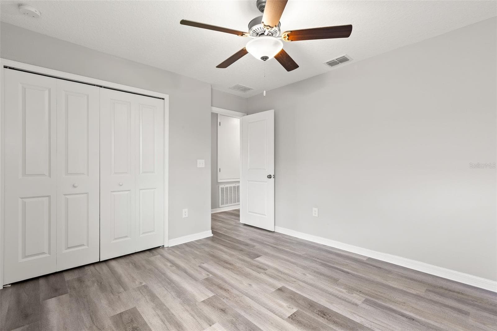 Bedroom 4 includes a wide double-door closet, newly replaced laminate flooring, fresh neutral paint and a ceiling fan, with plenty of wall space for a flexible furniture layout. - 5061 WHITE CHICORY DR, APOLLO BEACH