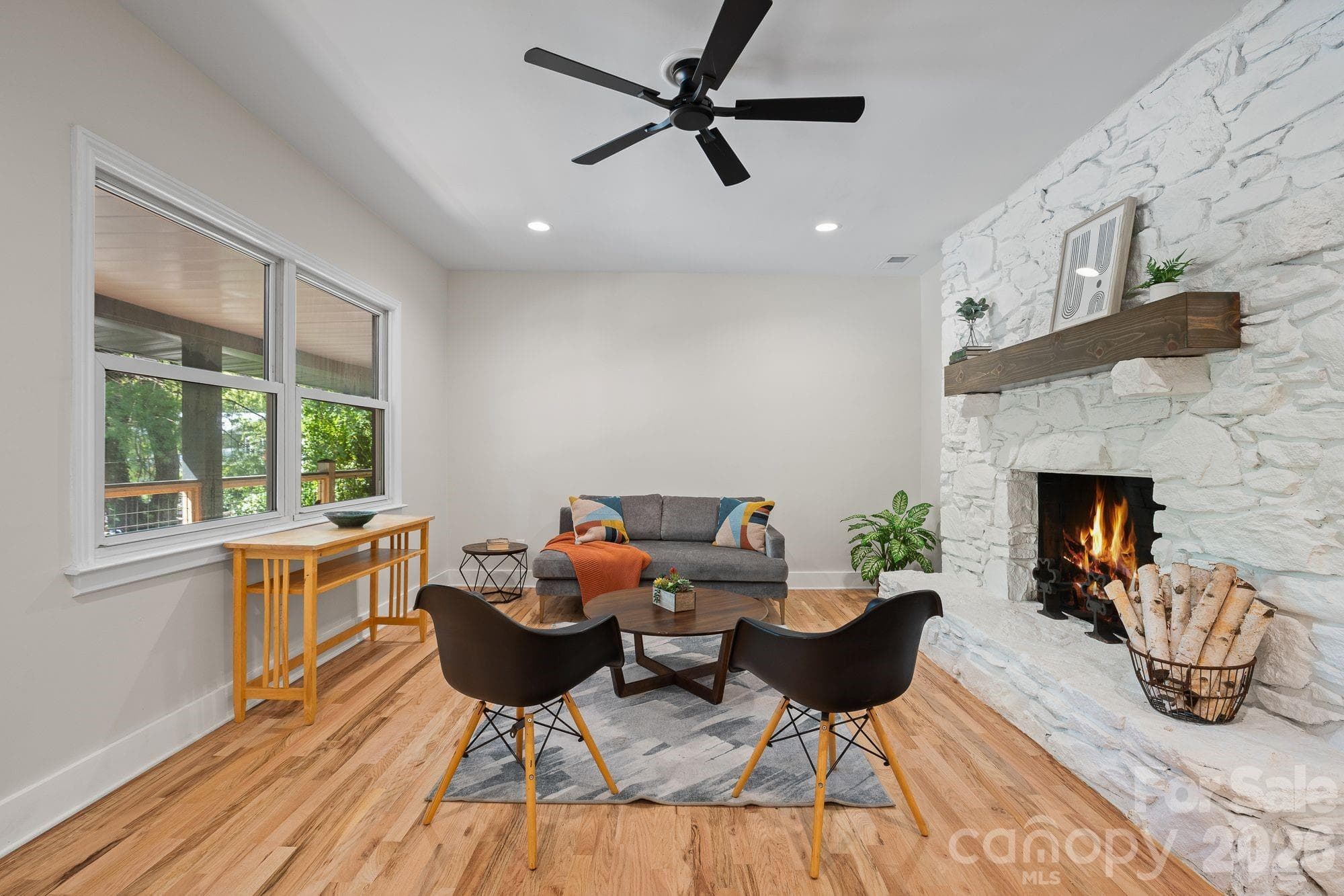 Living Room: Bright living room with stone wood-burning fireplace and abundant natural light. - 156 State Street, Asheville