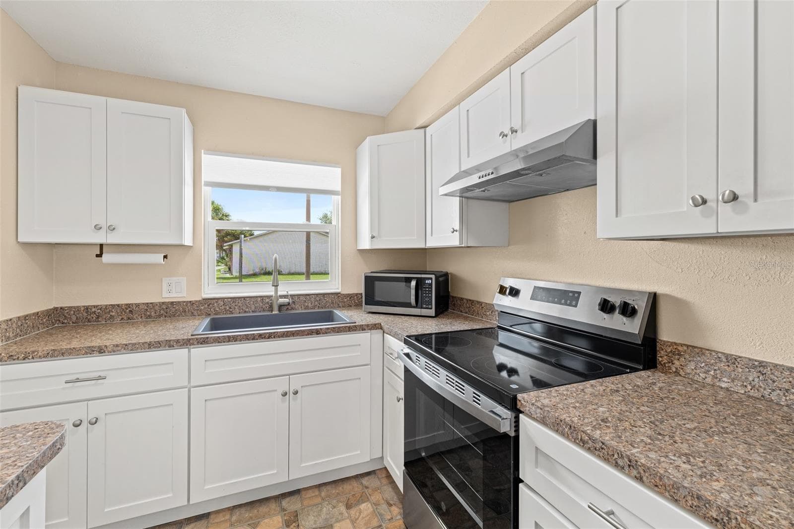Kitchen with white soft-close cabinetry, stainless range hood, and microwave - 1514 CLEARLAKE RD #2, COCOA