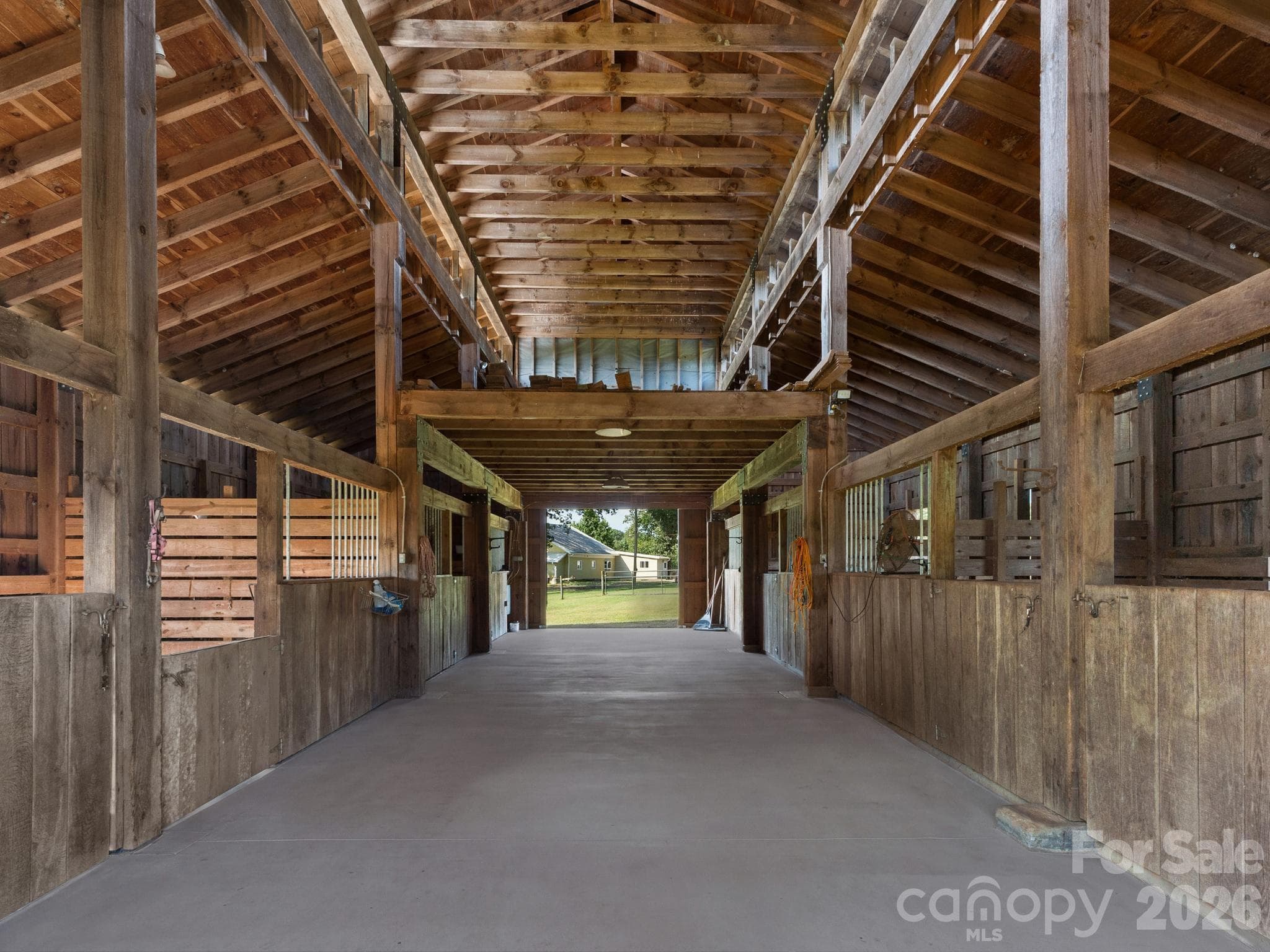 Wide aisle and high ceilings with ventilation creates a comfortable barn for horses and other animals. (note - the floor has been virtually cleaned up with an editing program) - 157 J A Hampton Road, Rutherfordton