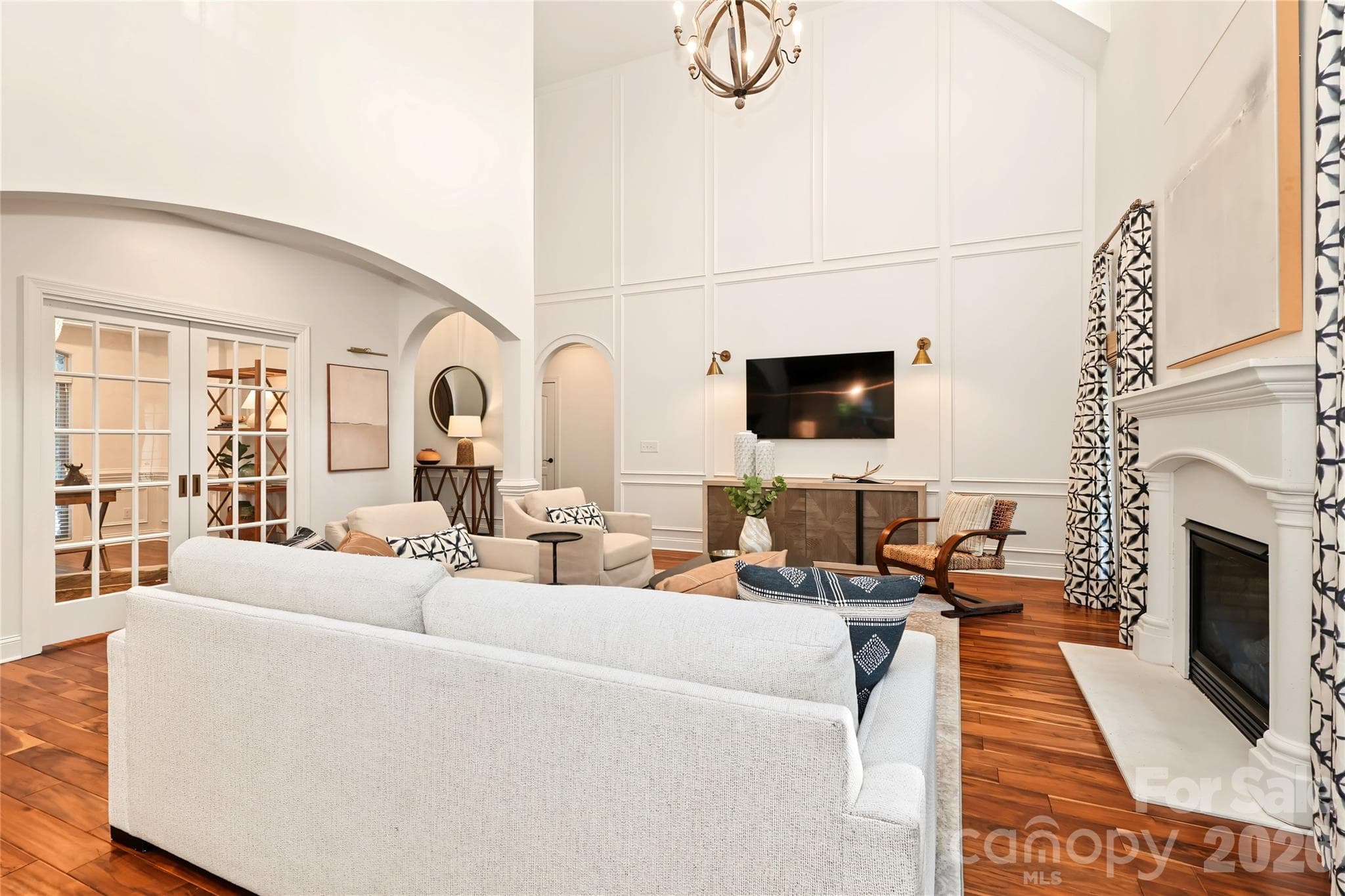 Living Room and Office. The arched doorway leads to the half bath to the left and the Primary Suite to the right. - 4934 Spalding Place, Charlotte