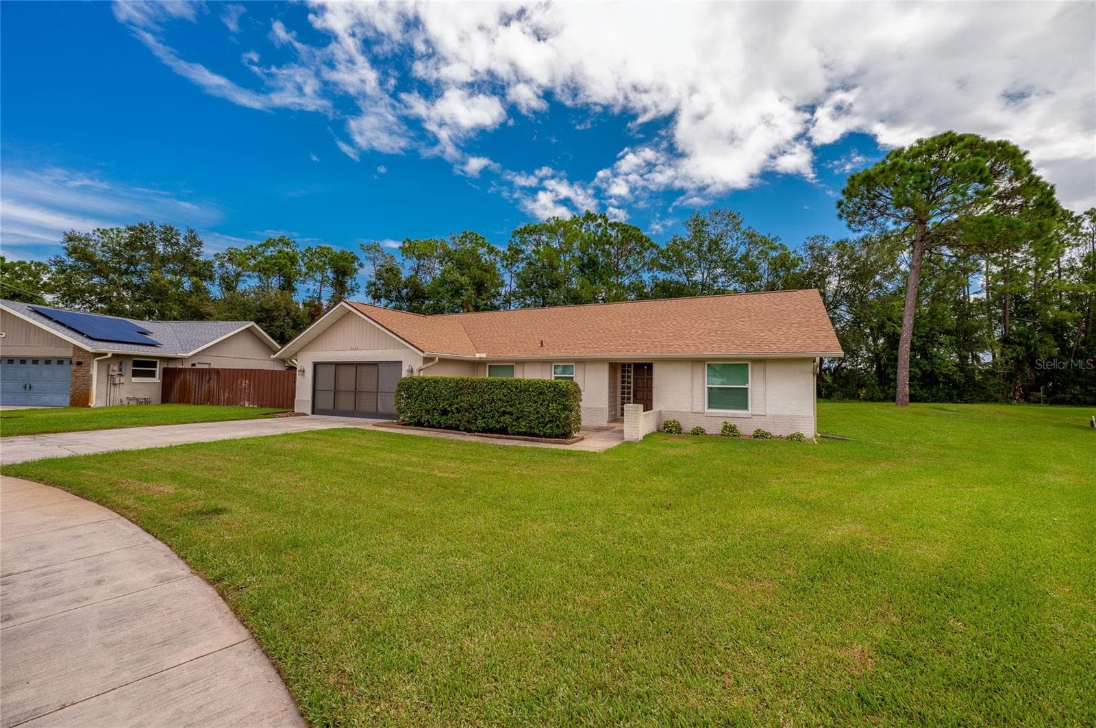 Charming single-story exterior showcasing a wide paved driveway, manicured green lawn, and low-maintenance landscaping. - 4669 SECRET RIVER TRL, PORT ORANGE