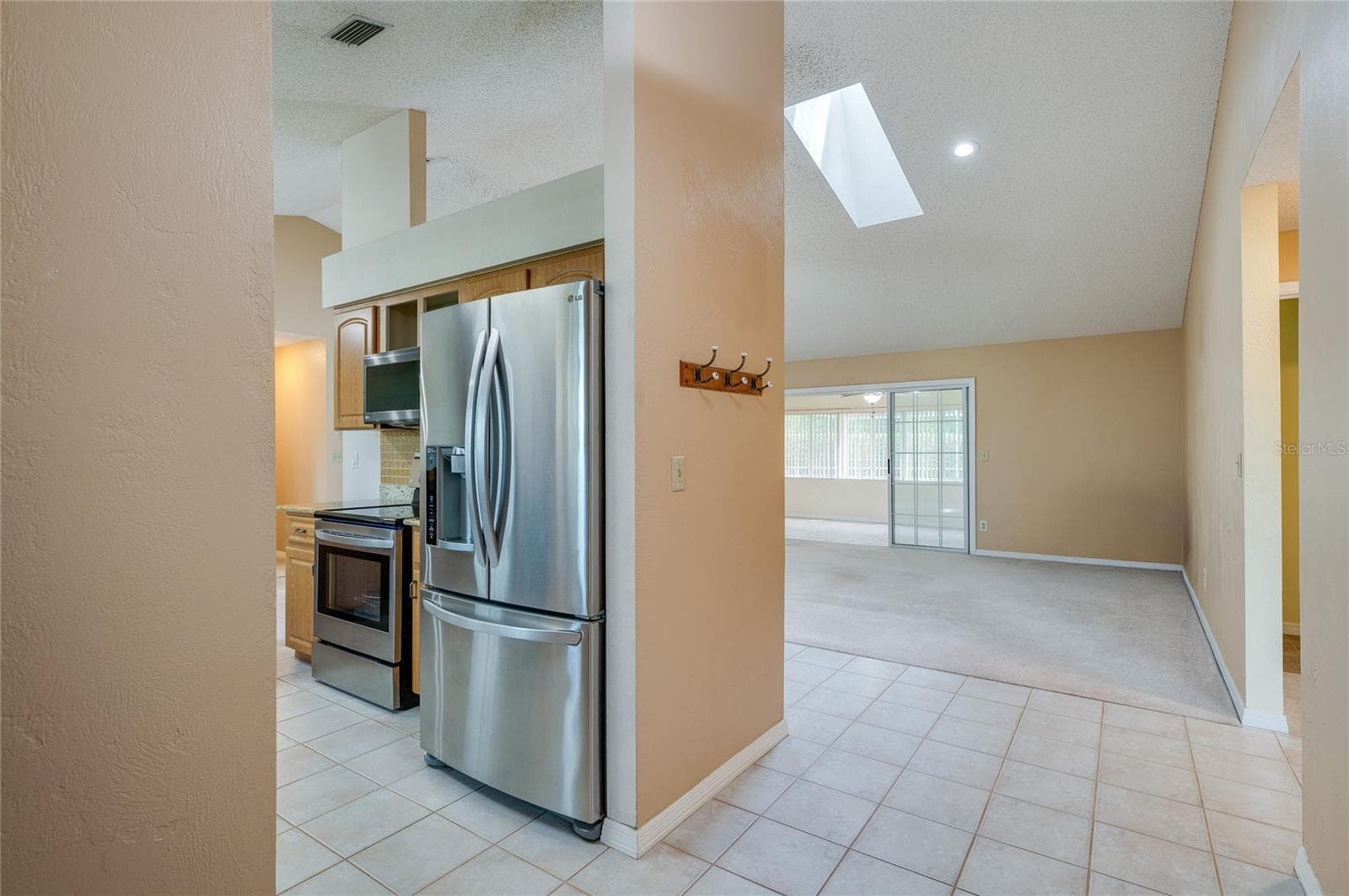 Functional kitchen nook outfitted with stainless steel appliances, modern tiling, and recessed lighting. Skylights overhead enhance the bright, open interior feel. - 4669 SECRET RIVER TRL, PORT ORANGE