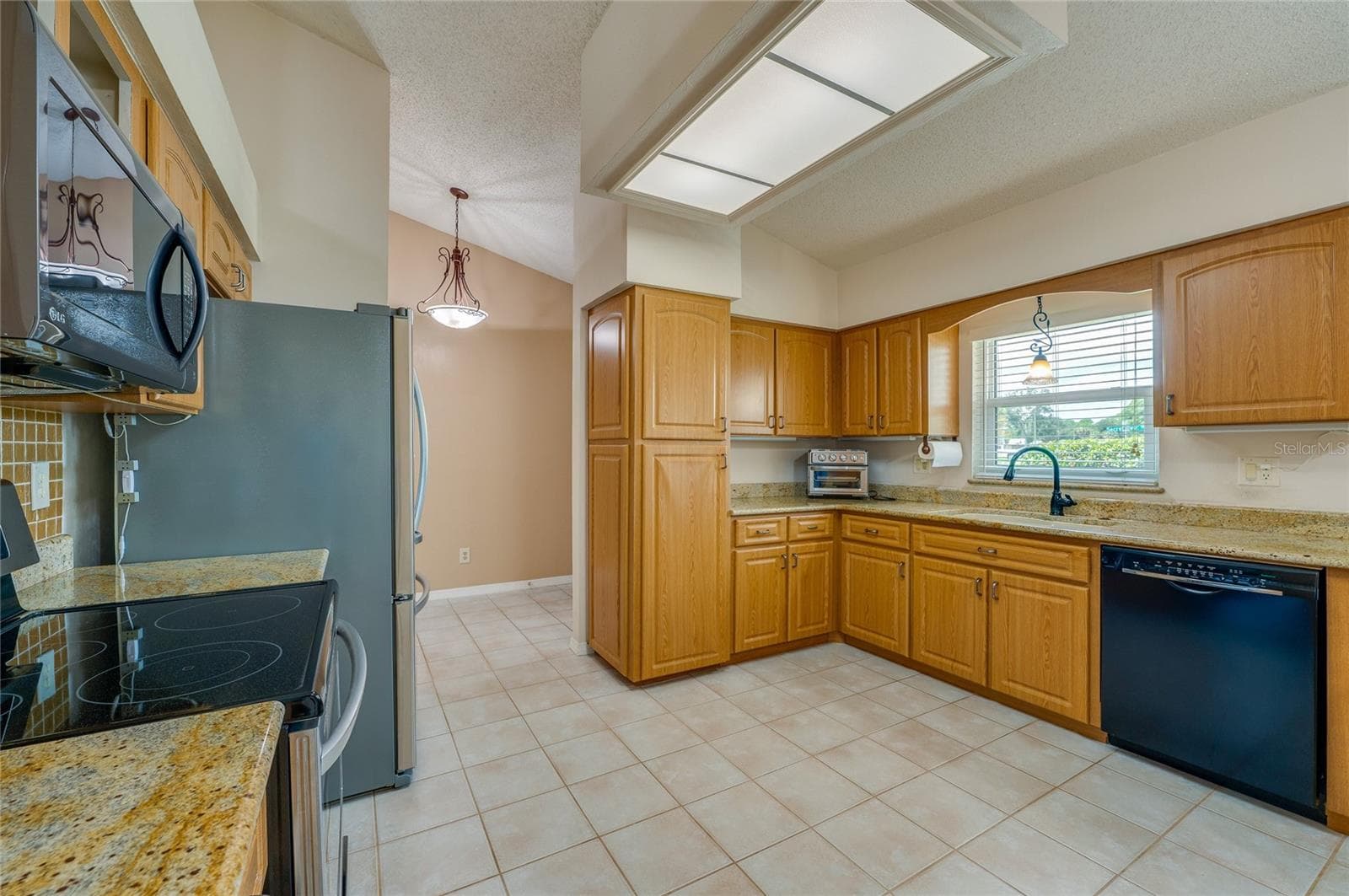 Well-appointed kitchen featuring solid wood cabinets, granite countertops, black and stainless steel appliances, and tile flooring. - 4669 SECRET RIVER TRL, PORT ORANGE