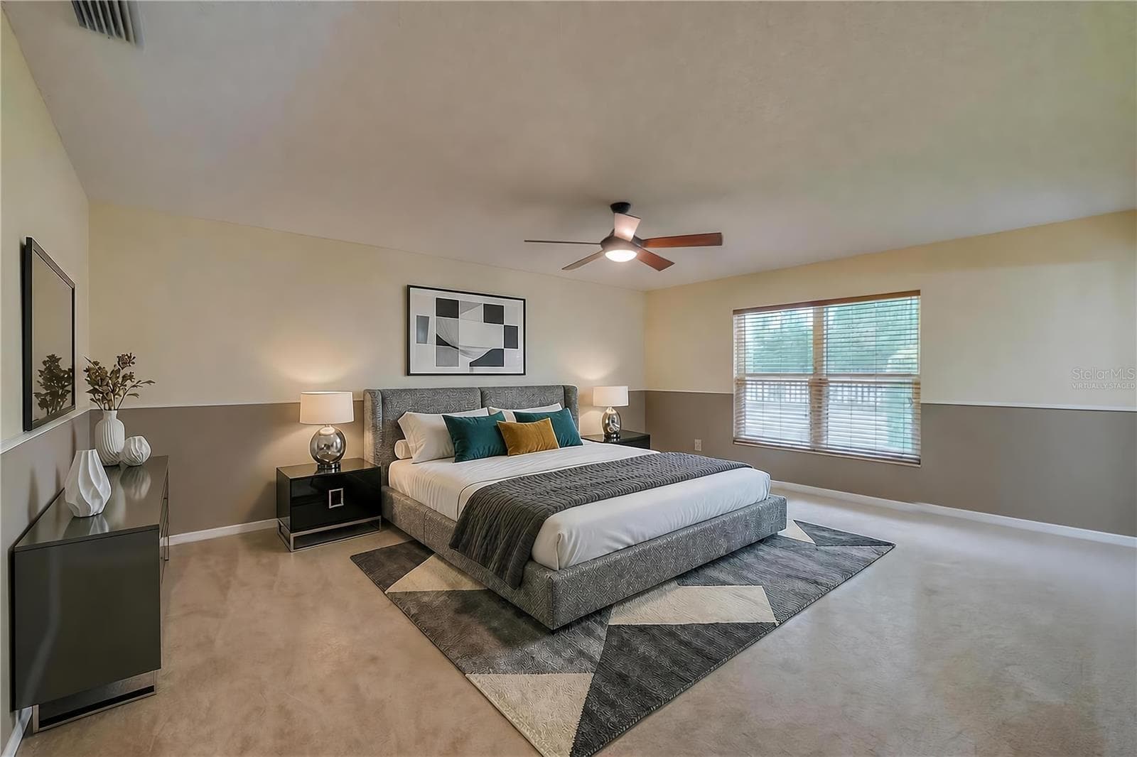 Virtually Staged - Spacious primary bedroom featuring soft carpeting, two-tone painted walls, a central ceiling fan, and a large window providing pleasant outdoor views. - 4669 SECRET RIVER TRL, PORT ORANGE
