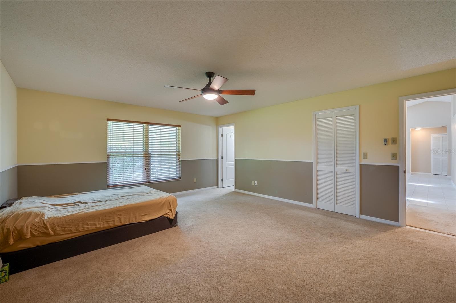 Generously sized bedroom offering wall-to-wall carpeting, two-tone neutral walls, a ceiling fan light fixture, and louvered closet doors. - 4669 SECRET RIVER TRL, PORT ORANGE