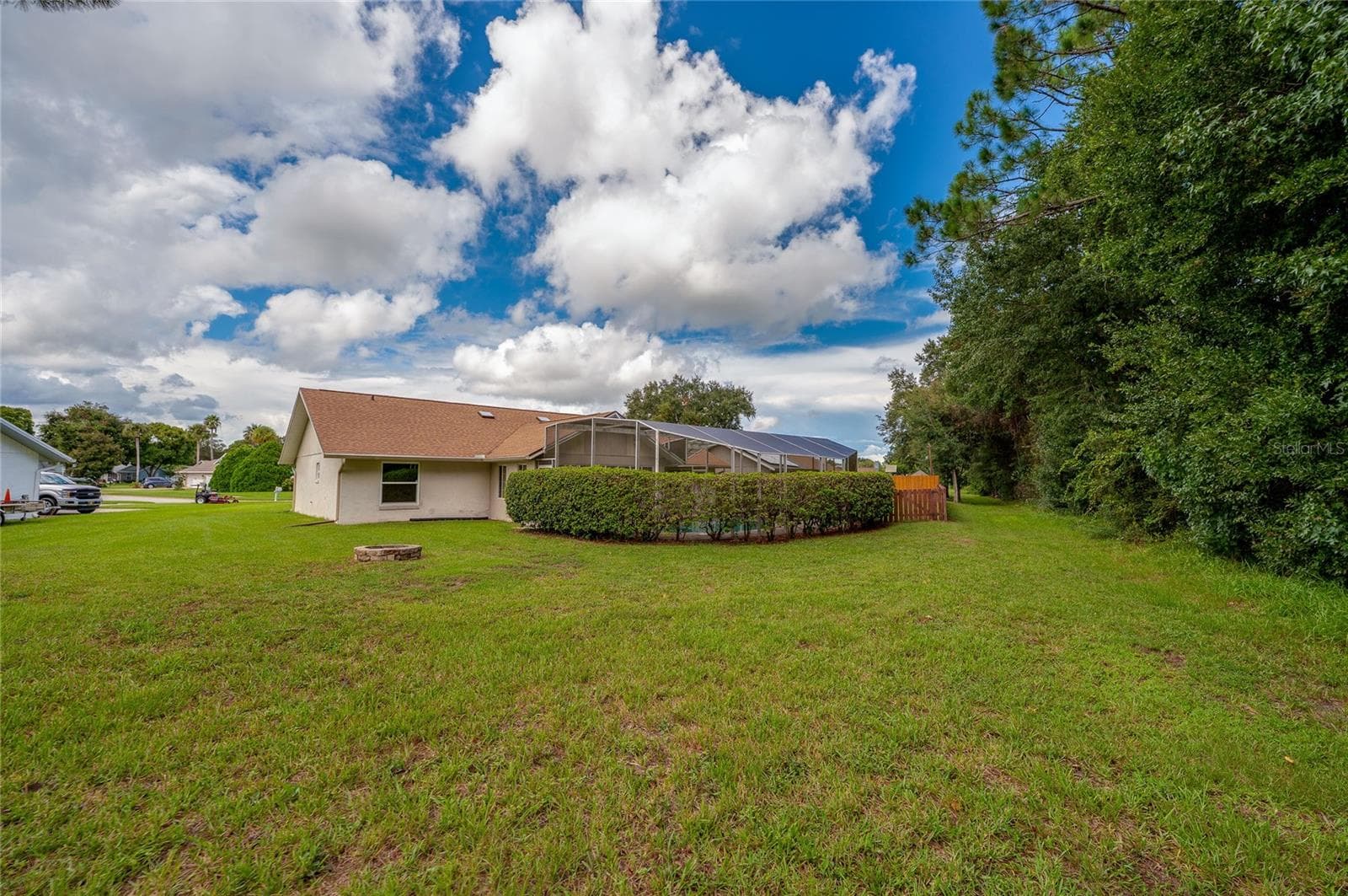 Wide view of the open lawn framing the rear exterior of the home, complete with lush green grass and mature privacy landscaping. - 4669 SECRET RIVER TRL, PORT ORANGE