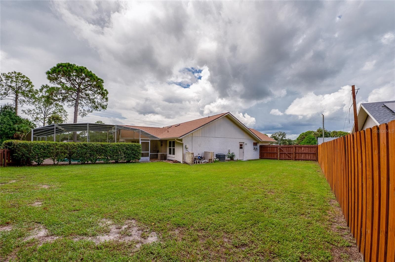 Full view of the rear elevation and spacious yard surrounded by a wooden privacy fence. - 4669 SECRET RIVER TRL, PORT ORANGE