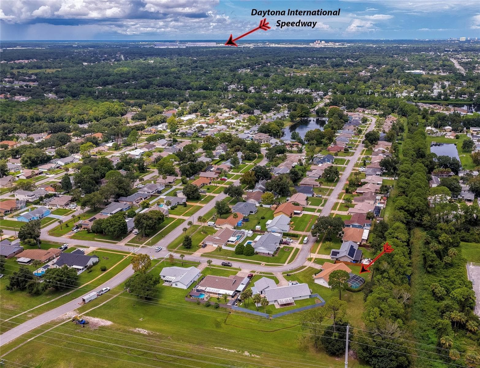 Broad aerial view pointing out the regional location relative to Daytona International Speedway and surrounding residential sectors. - 4669 SECRET RIVER TRL, PORT ORANGE