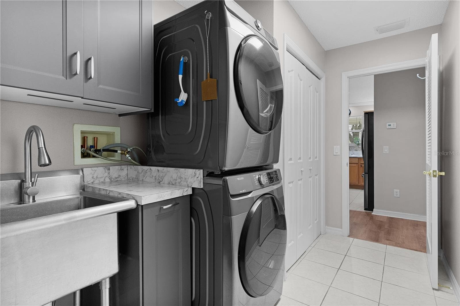 Laundry room with lots of cabinetry, mop sink & stackable washer/dryer - 2902 CHELTENHAM CT, THE VILLAGES