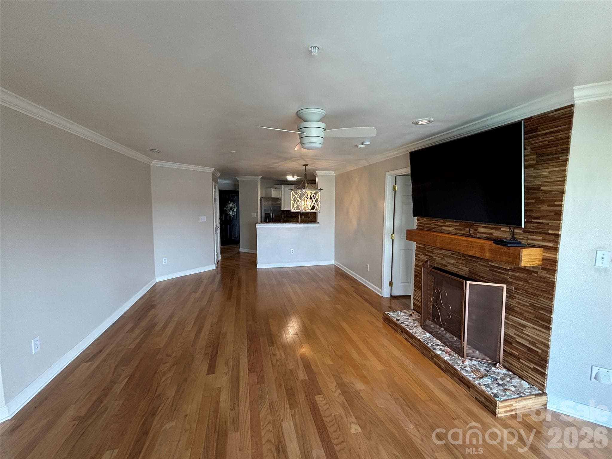 Beautiful custom coastal teakwood gas log fireplace in your liivng room with LG smart TV to remain. Looking from the glass sliders to the Kitchen. Dining area next to the half wall. - 1332 Torrence Circle, Davidson