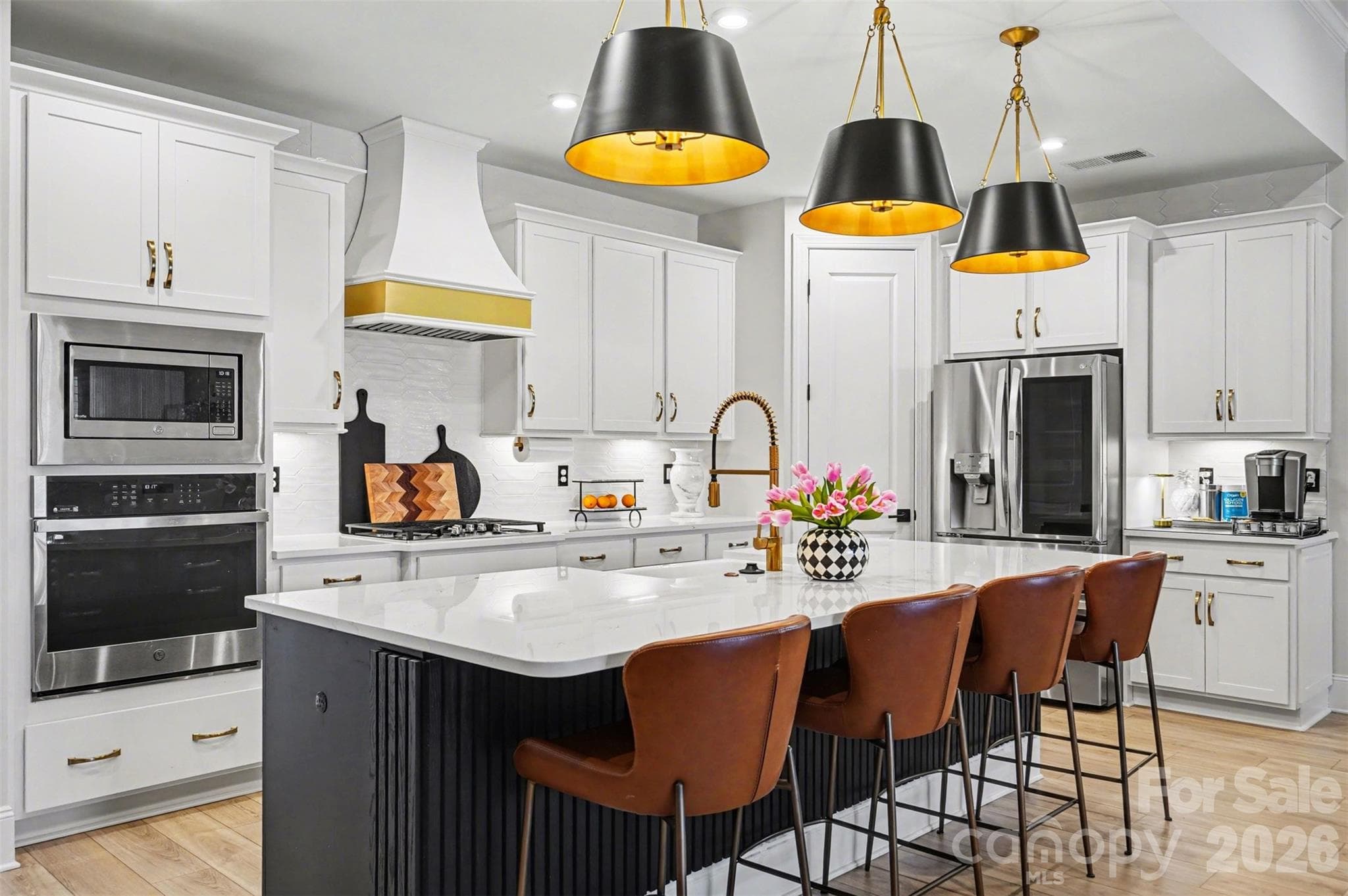 Custom hood with a gold band, gas cooktop, wall oven, and under-cabinet lighting. Built for people who actually cook. - 8027 Longwaters Court, York