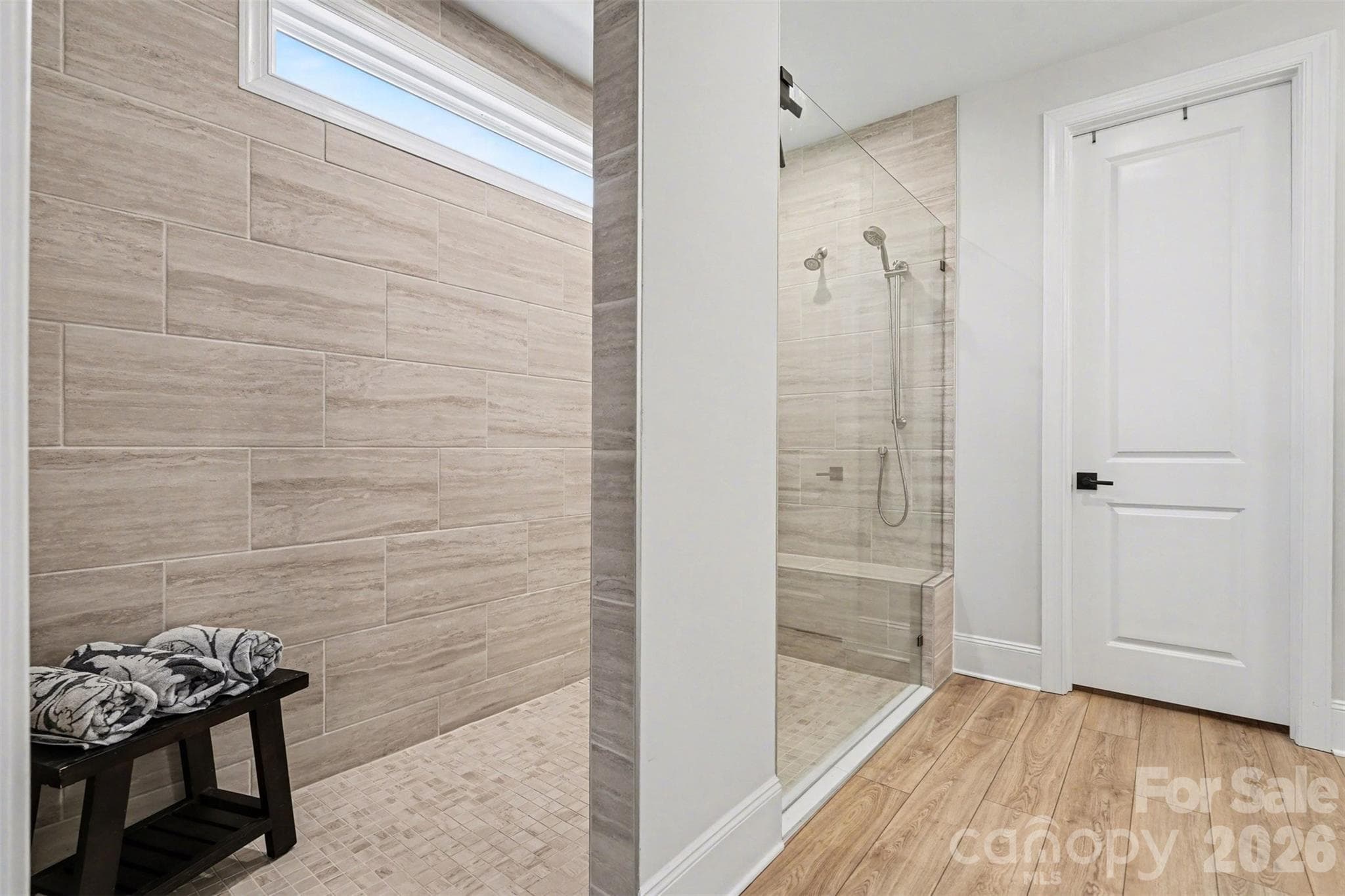 The primary shower is the real deal. Extended walk-in, bench, dual shower heads, and a transom window for daylight. - 8027 Longwaters Court, York
