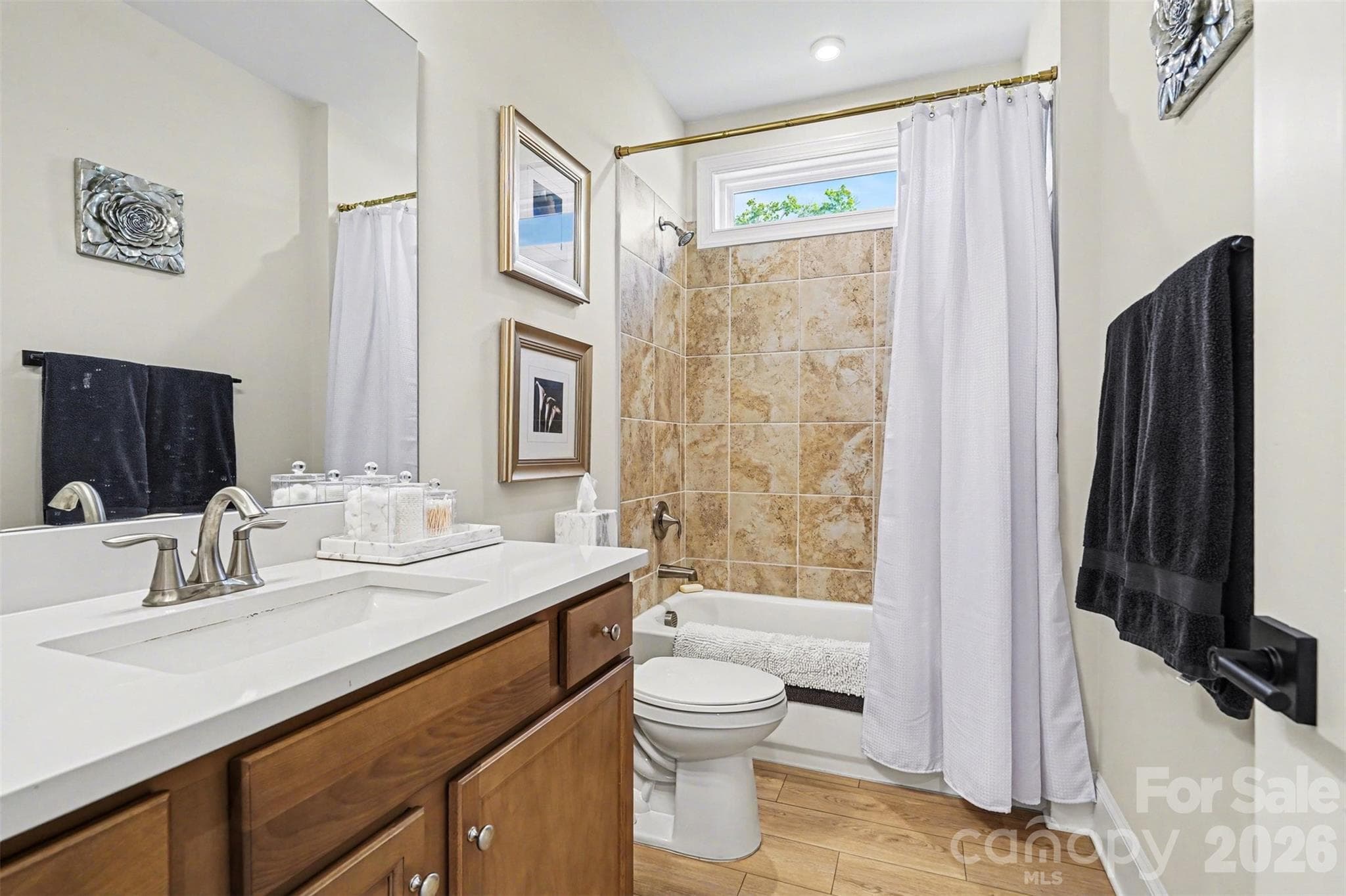 Hall bath with a tub and shower, quartz counter, and a window for natural light. - 8027 Longwaters Court, York