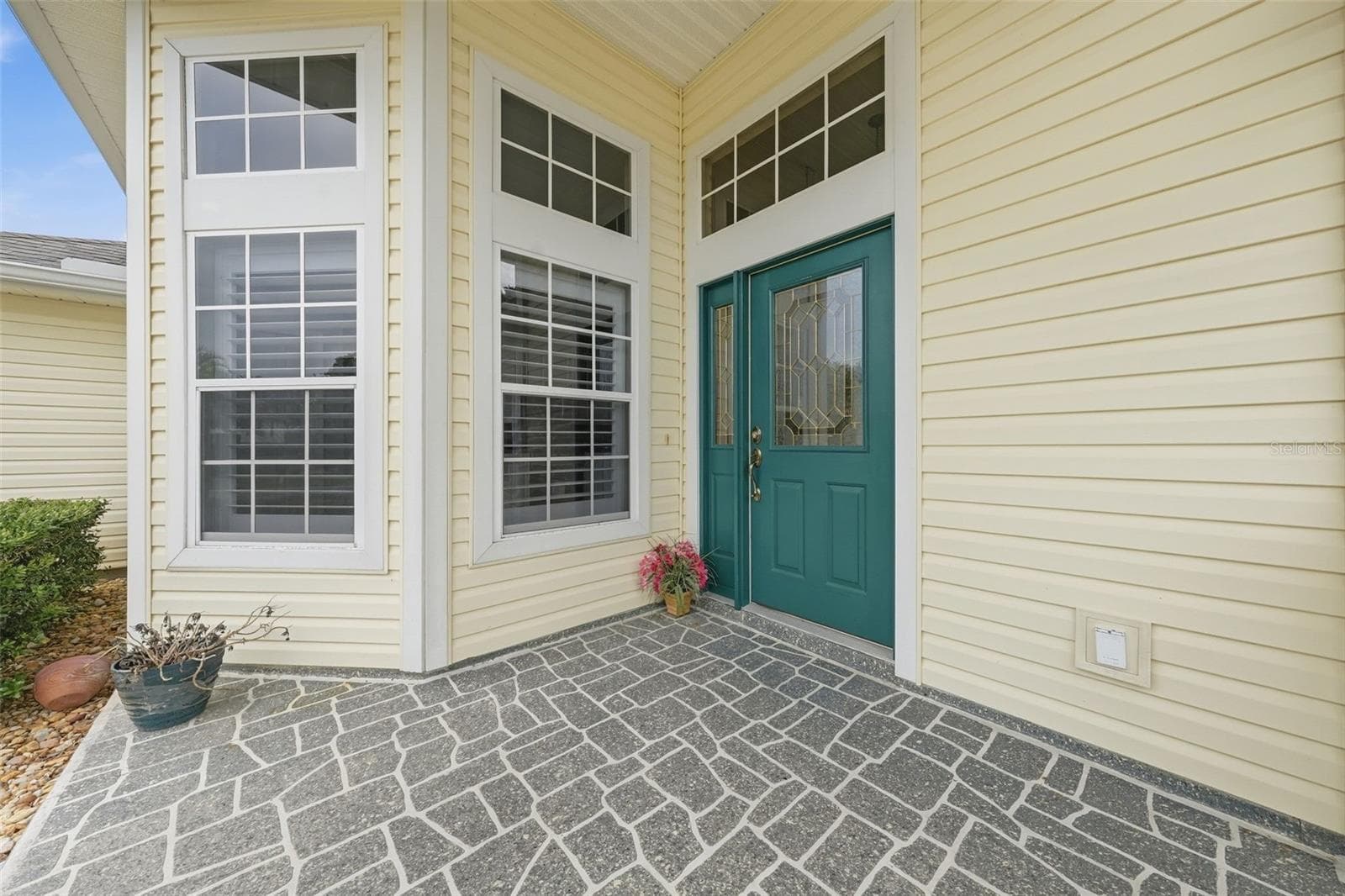 Welcoming covered entry with distinctive architectural windows and decoratice glass front door. - 5596 FREEPORT DR, TAVARES