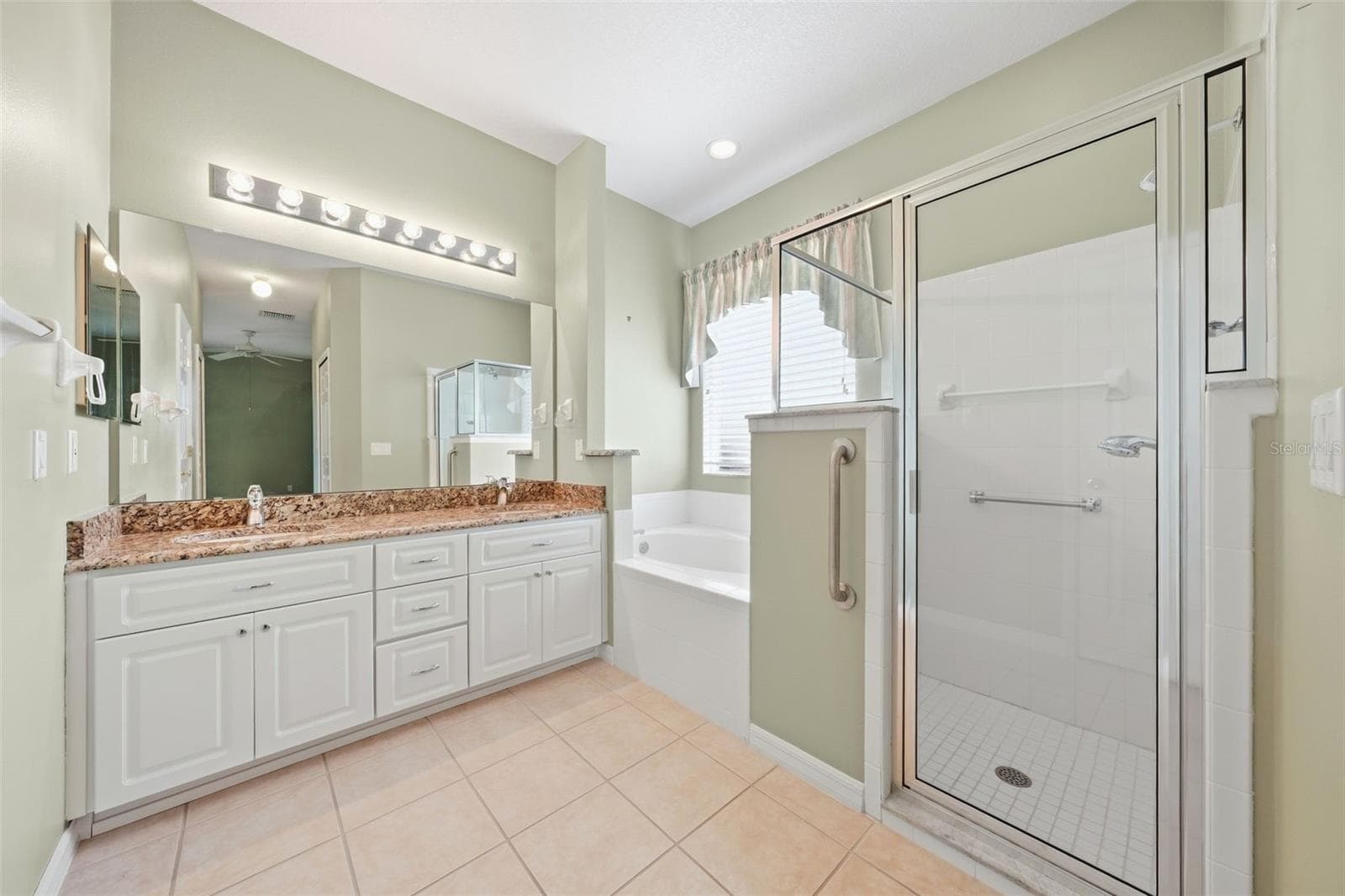 Spacious primary bath with granite vanity, soaking tub, and separate walk-in shower. - 5596 FREEPORT DR, TAVARES