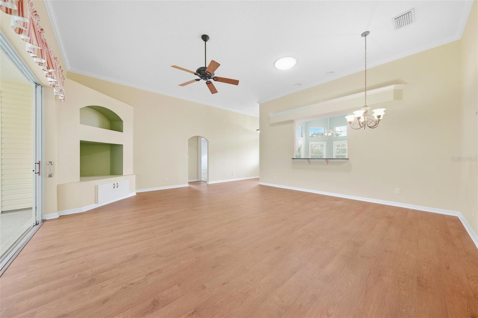 Spacious living area featuring a custome built-in entertainment center with architectural niches and warm wood flooring. - 5596 FREEPORT DR, TAVARES