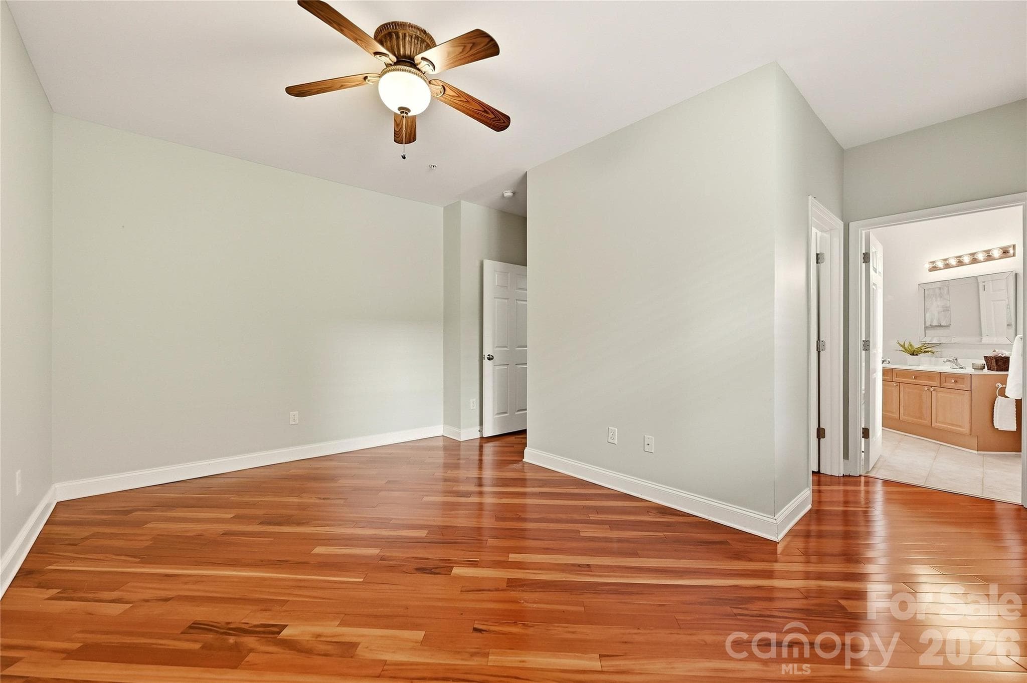 Bright secondary bedroom features hardwood floors, a ceiling fan, and flexible space for guests or a home office. - 9009 Rosalyn Glen Road, Cornelius