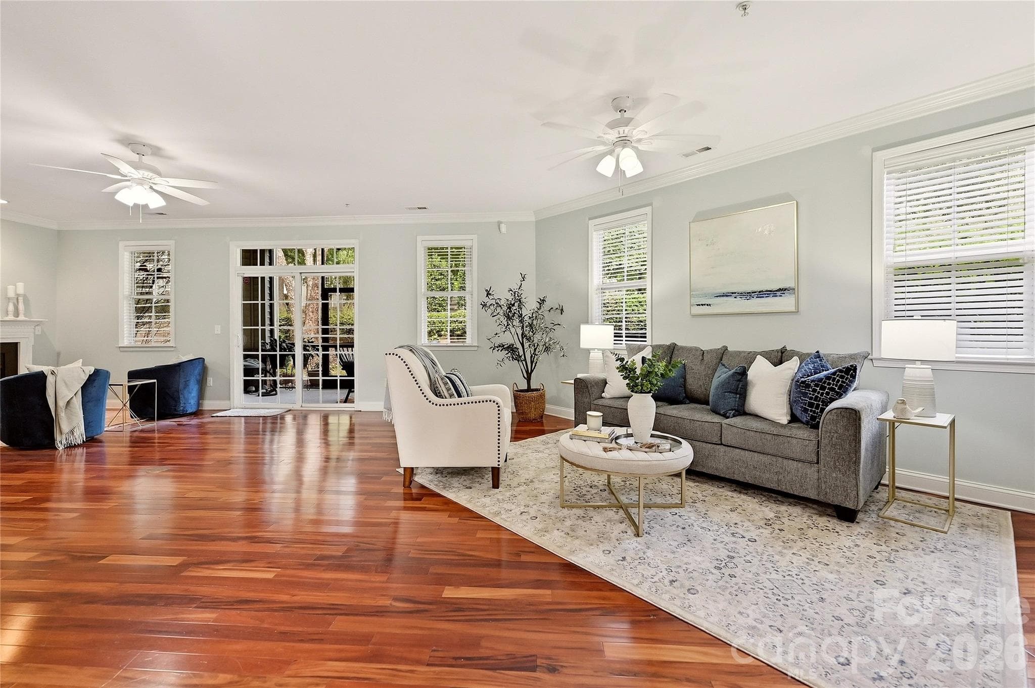 Bright living room features hardwood floors, a gas-log fireplace, ceiling fan, and abundant natural light. - 9009 Rosalyn Glen Road, Cornelius